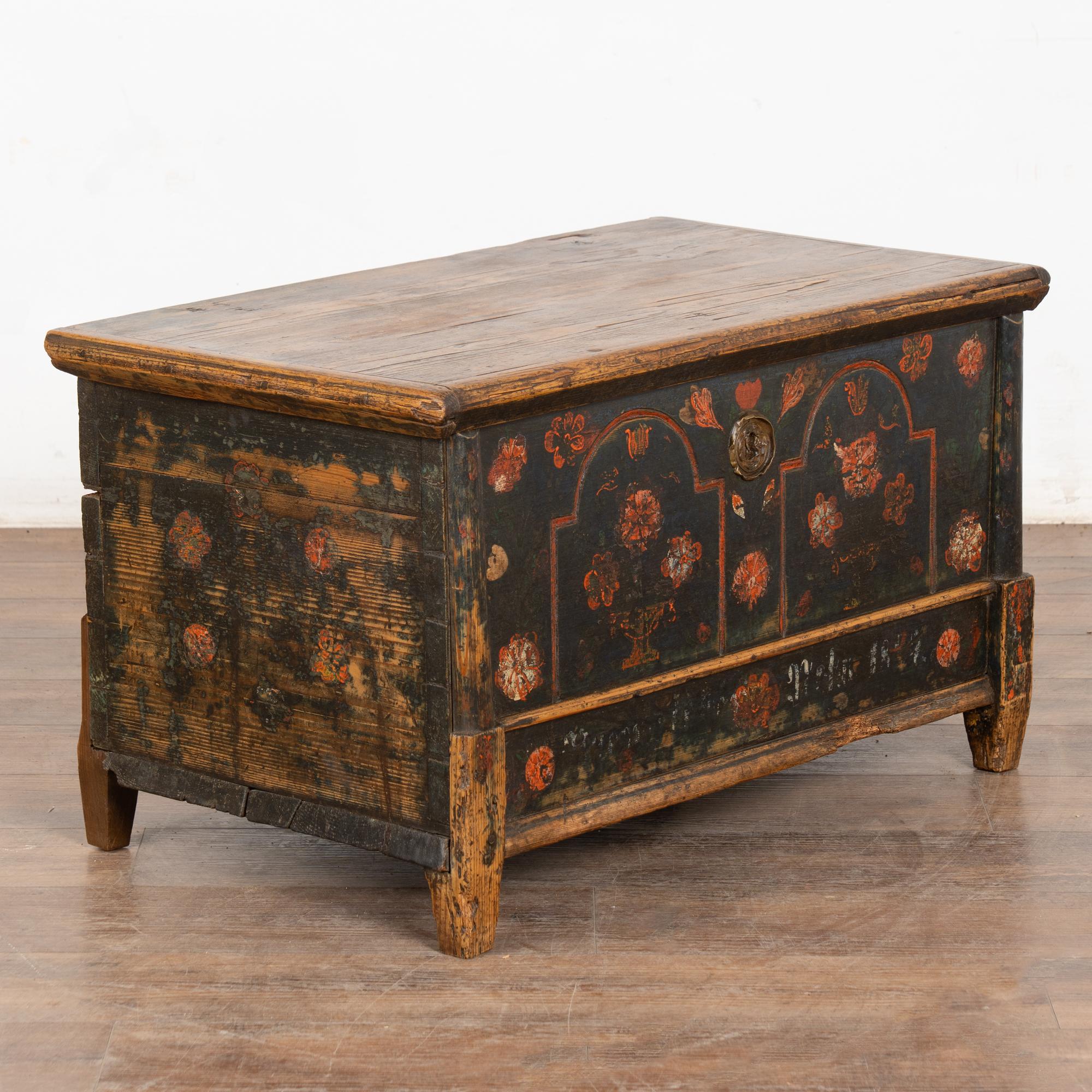 La finition peinte est entièrement d'origine sur ce coffre rustique en pin à dessus plat. Les fleurs étaient un ornement traditionnel, comme on peut le voir sur le devant de cette malle artisanale, où les fleurs rouges contrastent avec le fond bleu