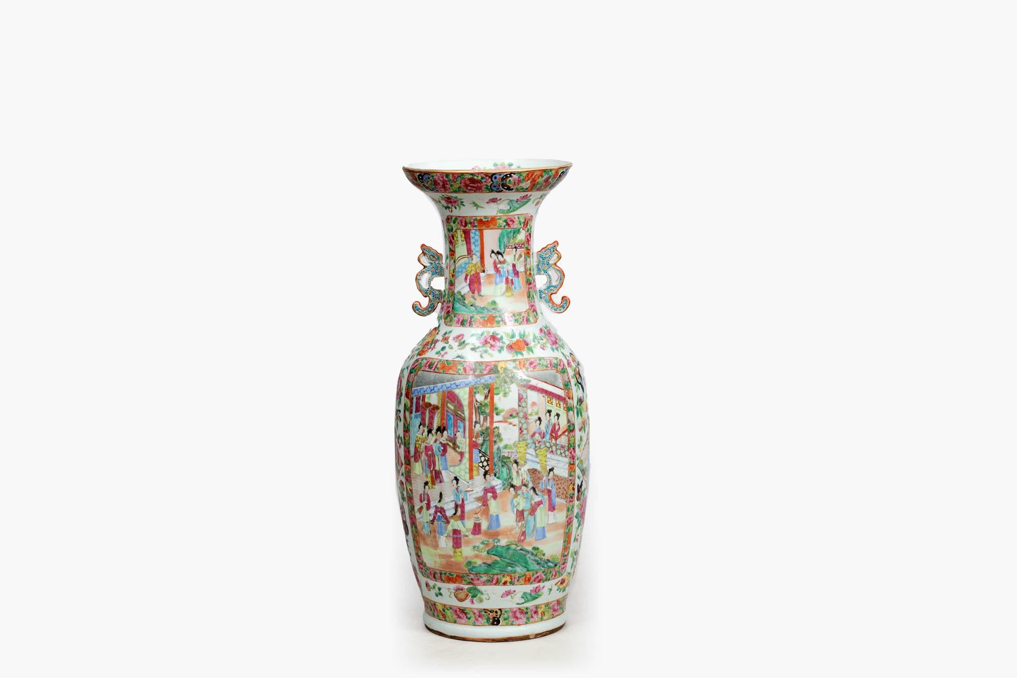 Handbemalte kantonesische Vase aus dem 19. Jahrhundert im Famille-Rose-Stil. Der balusterförmige Korpus mit hell bemalten Paneelen zeigt Innenszenen von Höflingen und ihren Dienern in üppig verzierten Blumenrabatten. Der Hals ist mit Drachengriffen