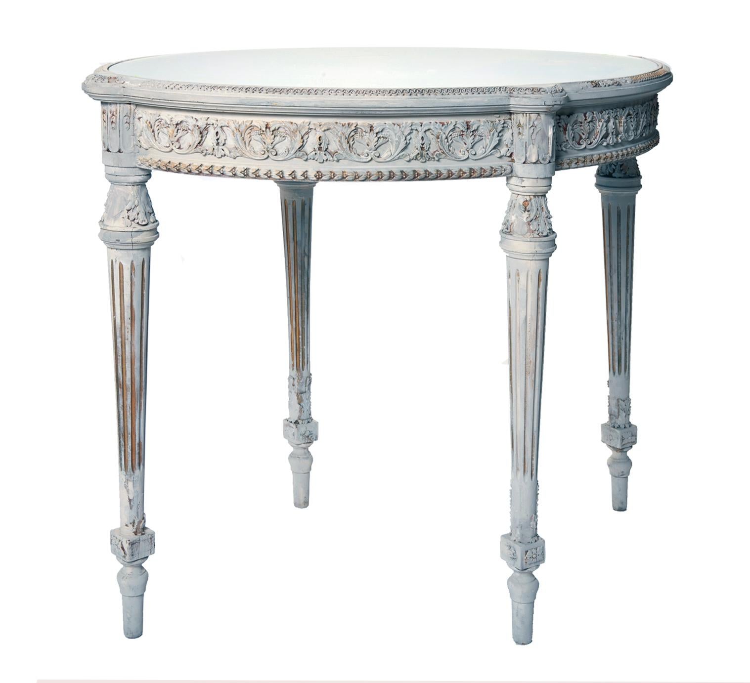 French? center table, originally with a dark marble top has been updated with a mirrored glass top which sits inside the rim. The top rim has a petite scroll pattern.
The apron with its classical pattern in gesso accented with gilding wax. 
The
