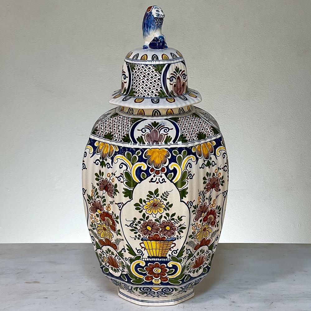 19th Century hand-painted lidded urn from Rouen is typical of the colorful and artistic works from the storied region, capturing the vivid natural hues of the region onto timeless classical forms. The faceted urn tapers to a narrower circular