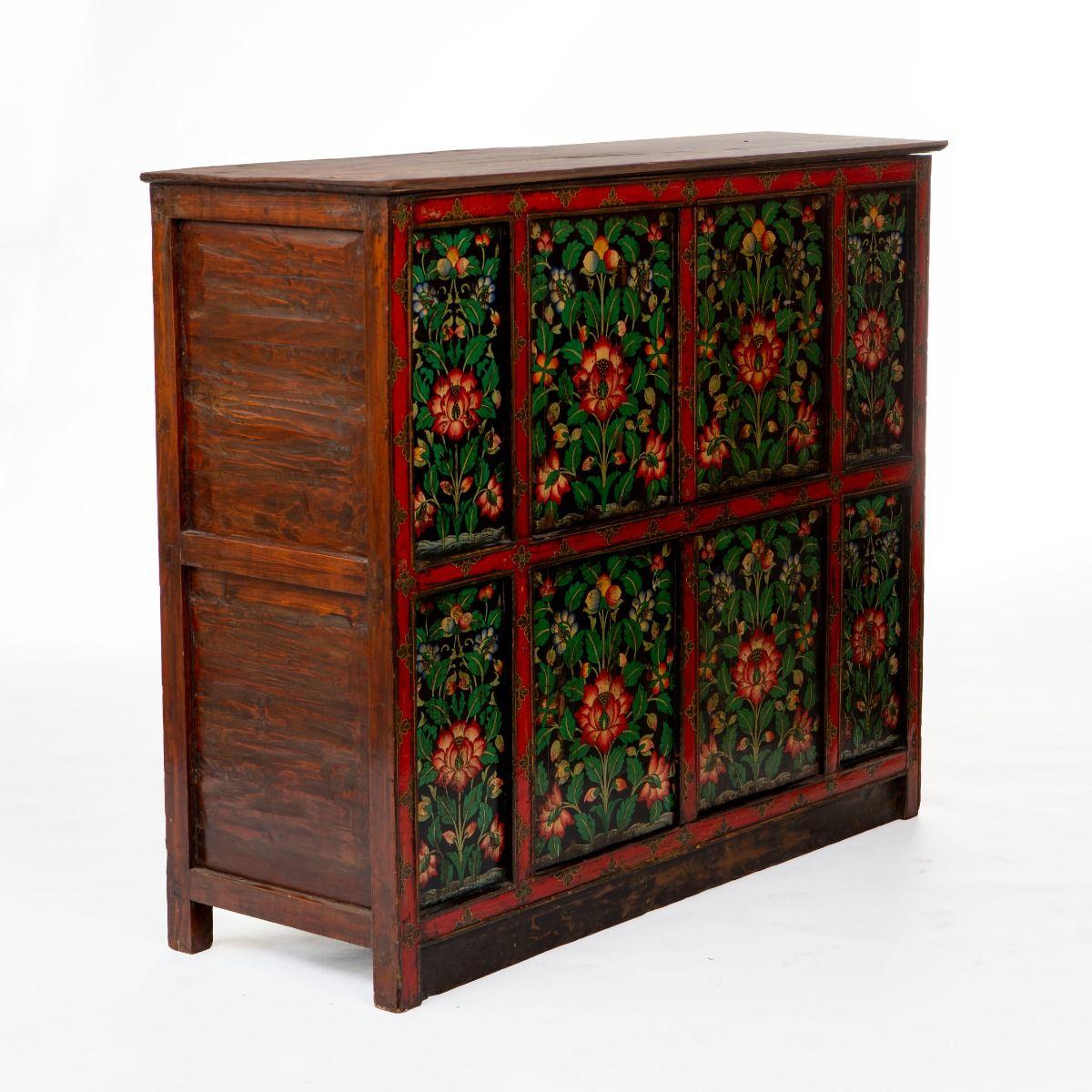 Tibetan cabinet in original condition, made of pinewood and hand-painted in polychrome lacquer colors.

The cabinet features two pairs of doors, one set above and one below.
The front is decorated with lotus flowers and leaf patterns framed in red