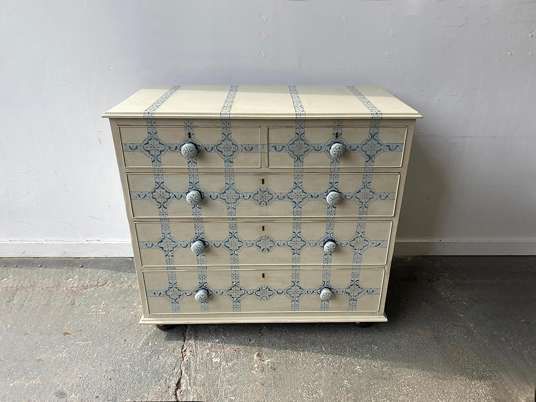 This late 19th century antique chest of drawers has been hand-painted with a delicate design inspired by Dutch Delft Blue pottery.

The chest is solid wood and of sturdy construction. It has the original handles and sits on the original rounded