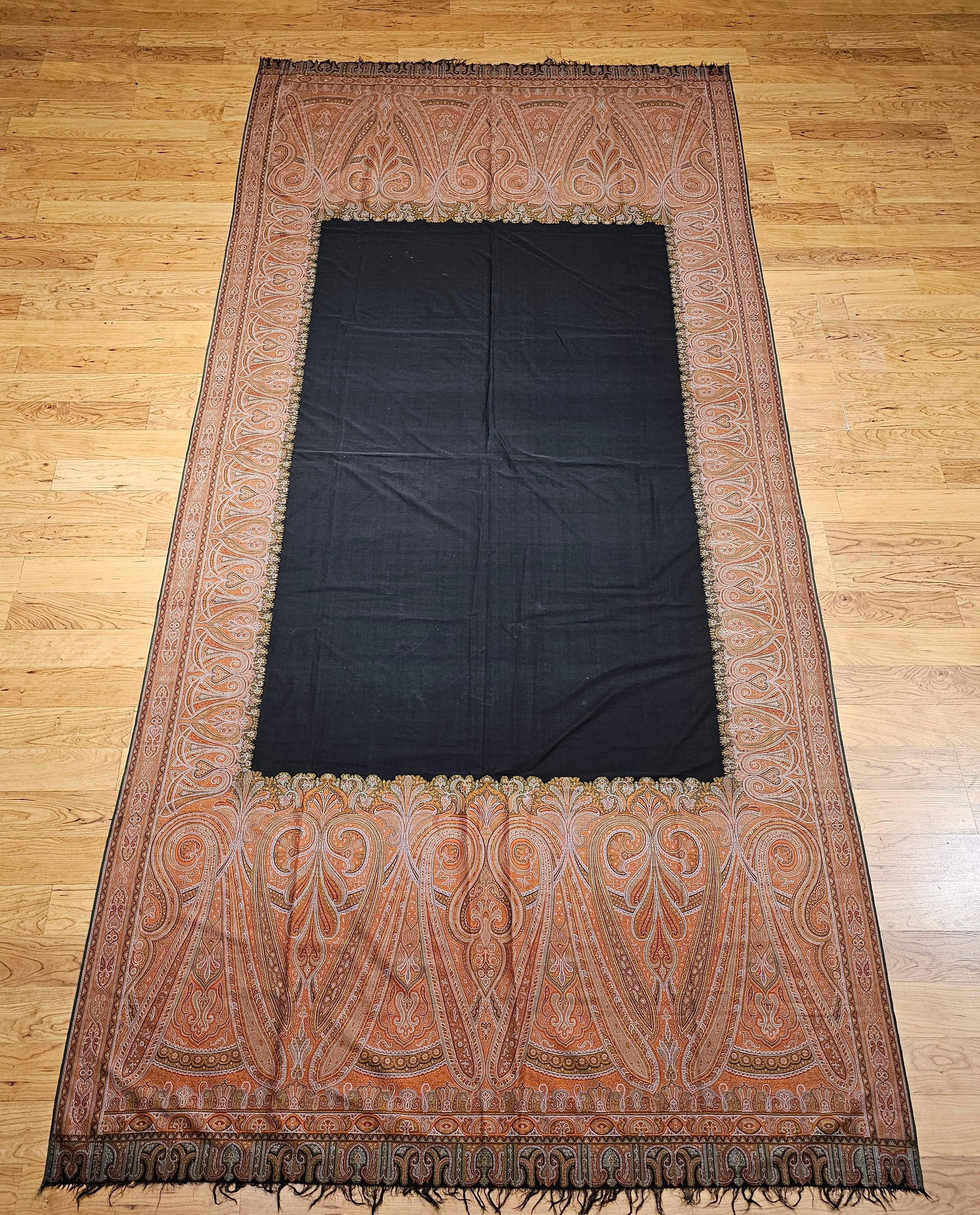 19th Century hand -woven Kashmiri Paisley Shawl from NW India in brick red, ivory, black and green.  The shawl has a paisley pattern as the border with larger paisley form on each end with a center part of the shawl woven in a blank black material. 