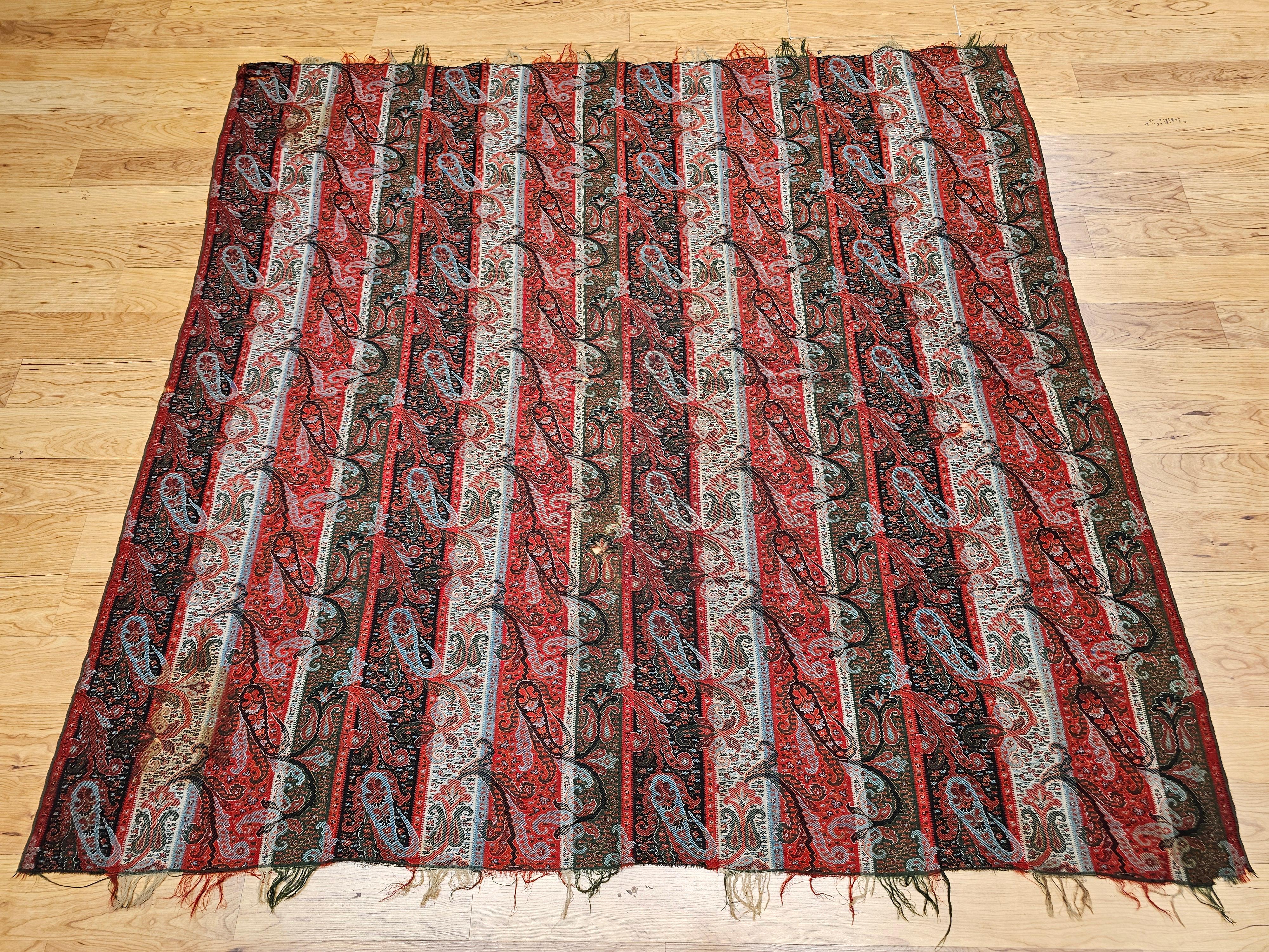  An exquisite 19th-century hand-woven Paisley shawl from Northwest India, featuring an elegant color palette of brick red, ivory, black, and green. This historic textile showcases a finely detailed paisley border, with larger stylized boteh