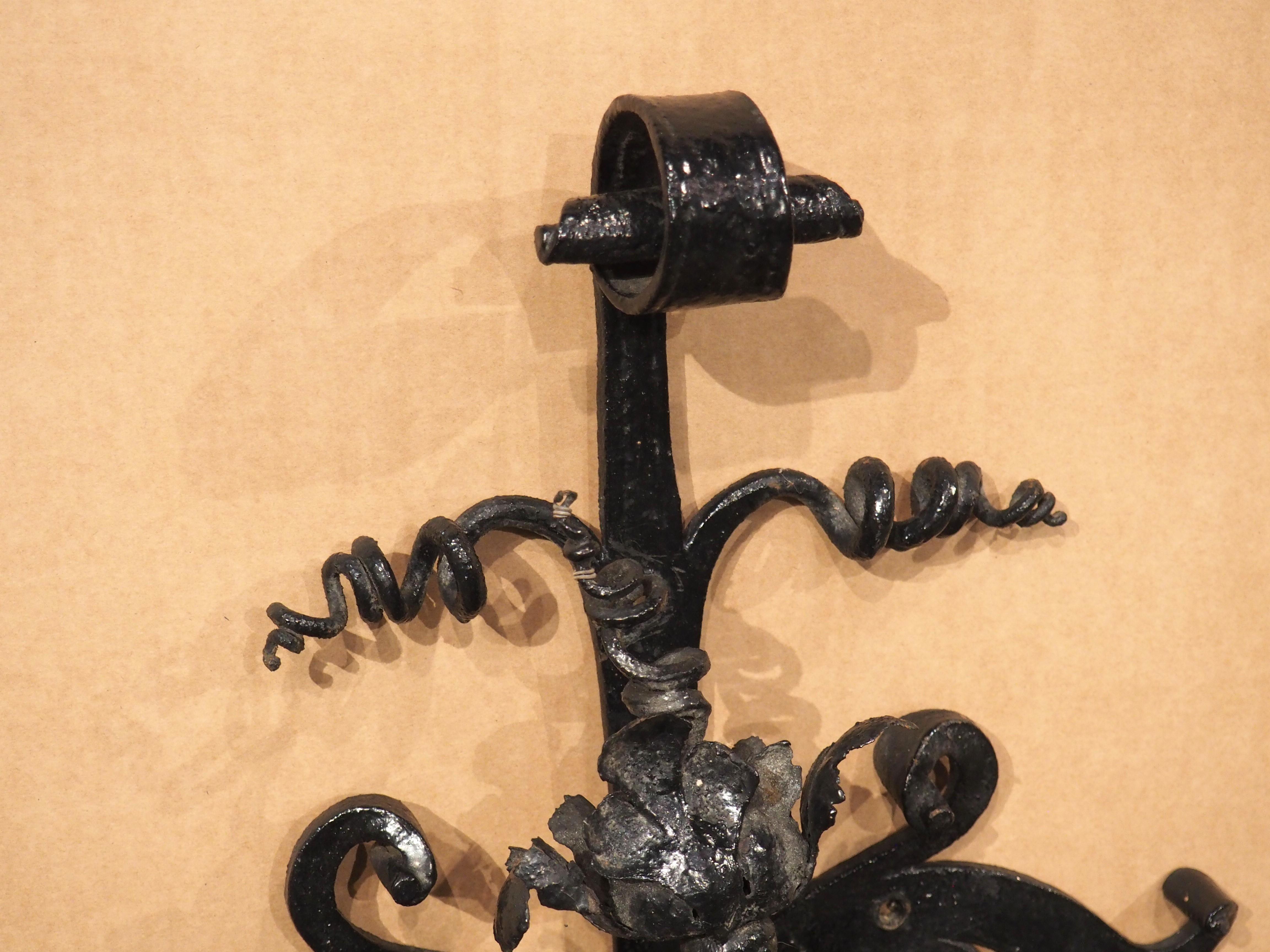 A true work of art, featuring a resplendent display of foliage and scrolls, this iron wall bell was hand-wrought in France during the 1800s. The bell is nestled within an ornate display of foliate rinceaux accented by corkscrew tendrils and volutes.