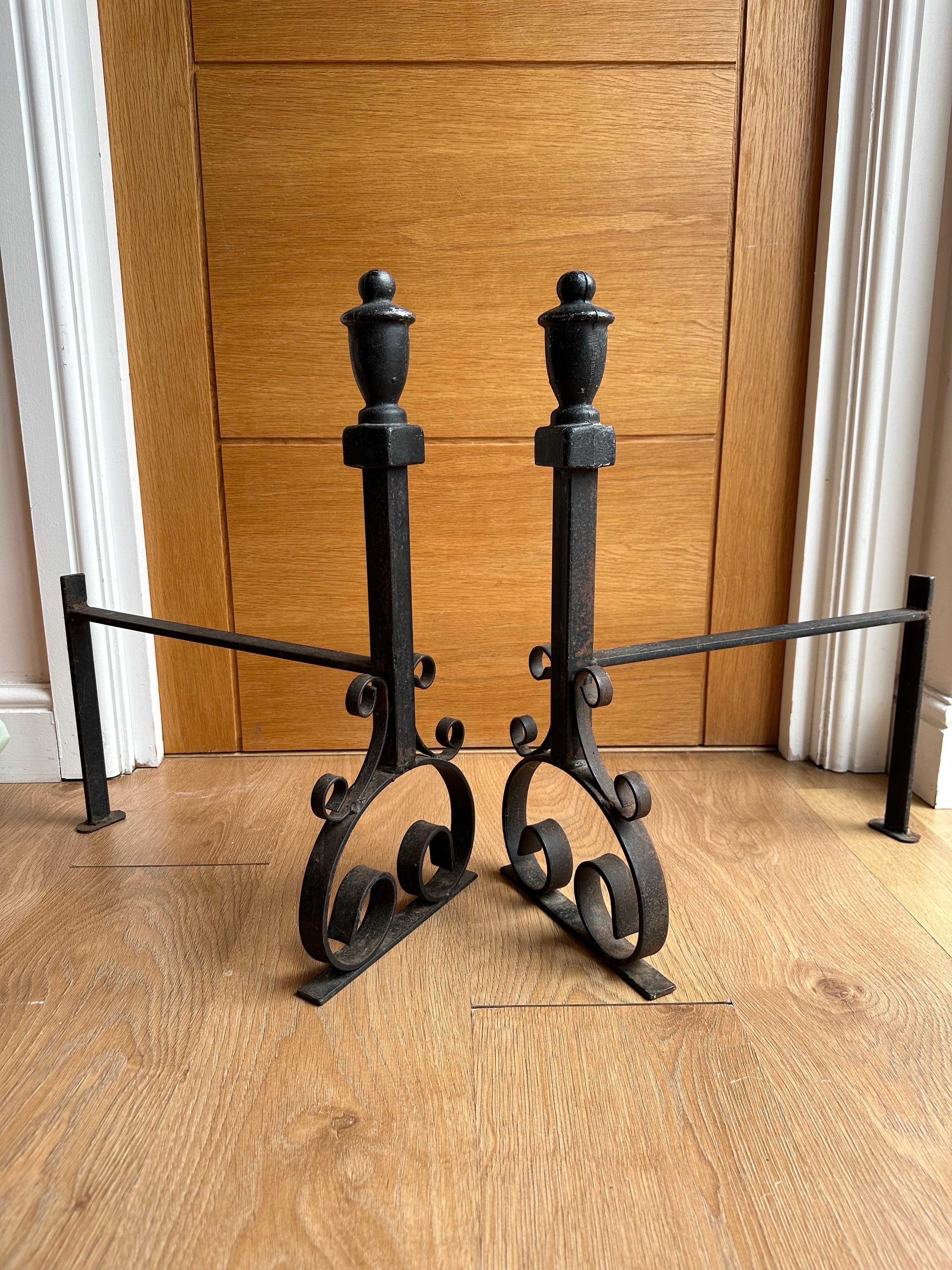 A large pair of 19th century handwrought iron Gothic fireplace andirons firedogs. This pair are completely wrought by hand out of very thick iron and have a dark black finish, crafted with swirled legs and shafts with beautifully wrought floral
