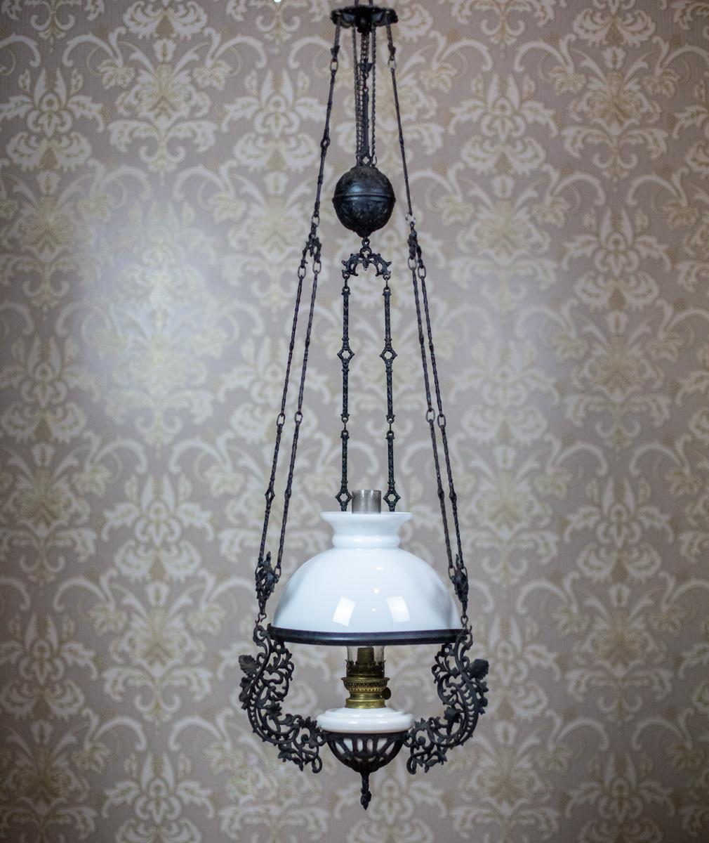 We present you a big, heavy hanging kerosene lamp from the late 19th century.
The lamp is made of cast iron. The font is ceramic, whereas the shade is made of milky glass.

This item is complete and in very good condition. The shade is undamaged.