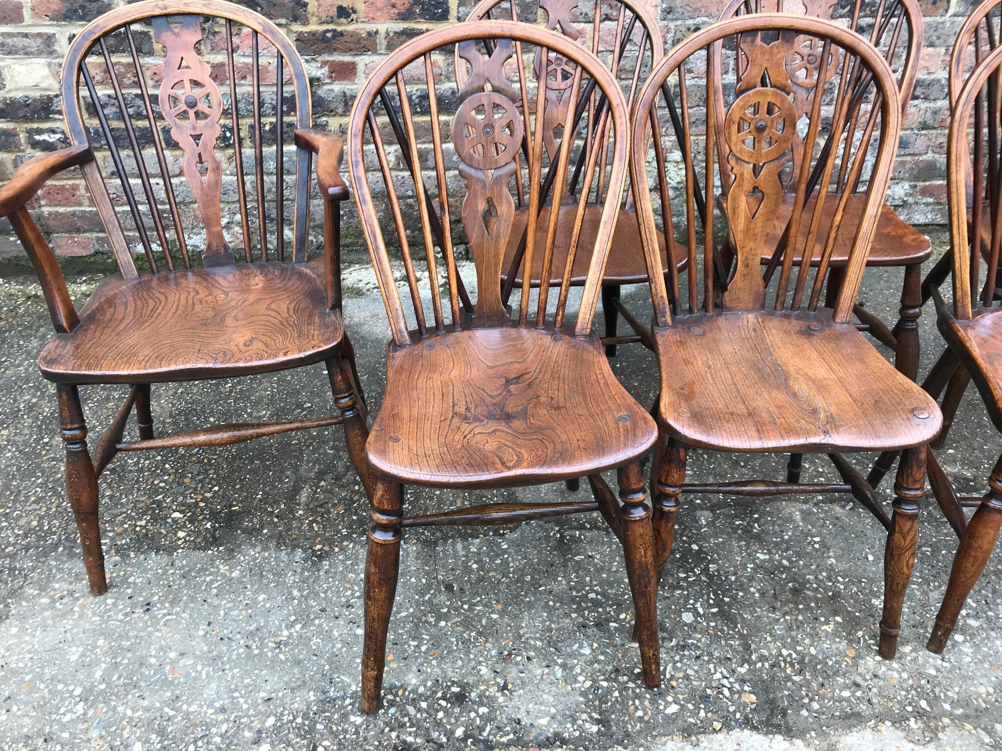 19th century set of six and two carver wheel back windsor chairs. The hoop backs enclosing a fretted centre splat with pierced wheel motif flanked by six turned spindles. The elm seats stand on turned legs.