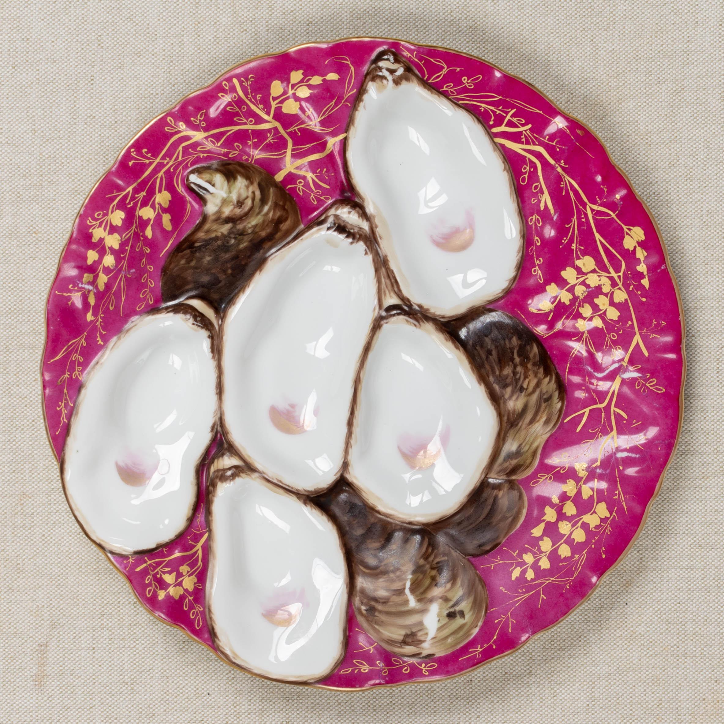 A 19th Century French Limoges porcelain turkey oyster plate with five white wells and brown shells on cranberry ground. Decorated with delicate hand-painted gilt branches and gilt trimmed rim. Unmarked. Circa 1880-1900. 
Dimensions: 8.5