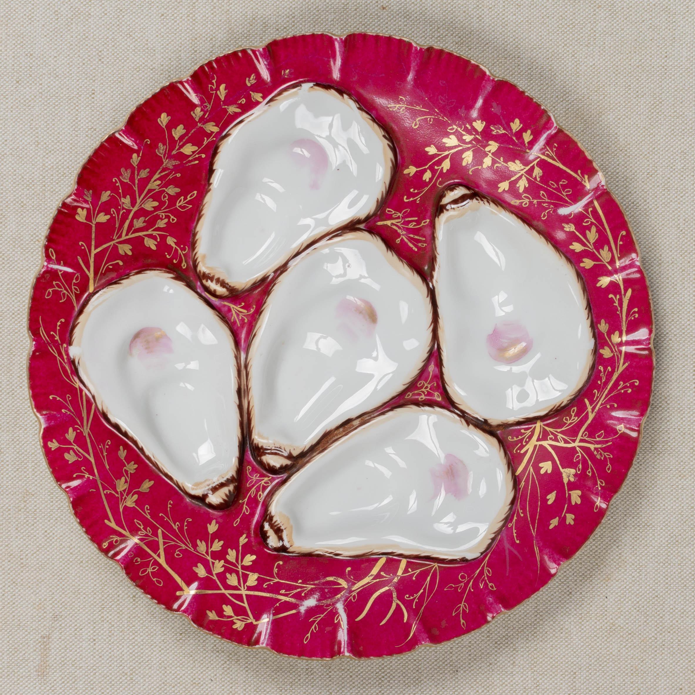 A 19th Century French turkey oyster porcelain plate with five white wells on raspberry pink ground. Decorated with delicate hand-painted gilt branches and gilt trimmed ruffled rim. Unmarked. Circa 1880-1900. 
Dimensions: 8.5