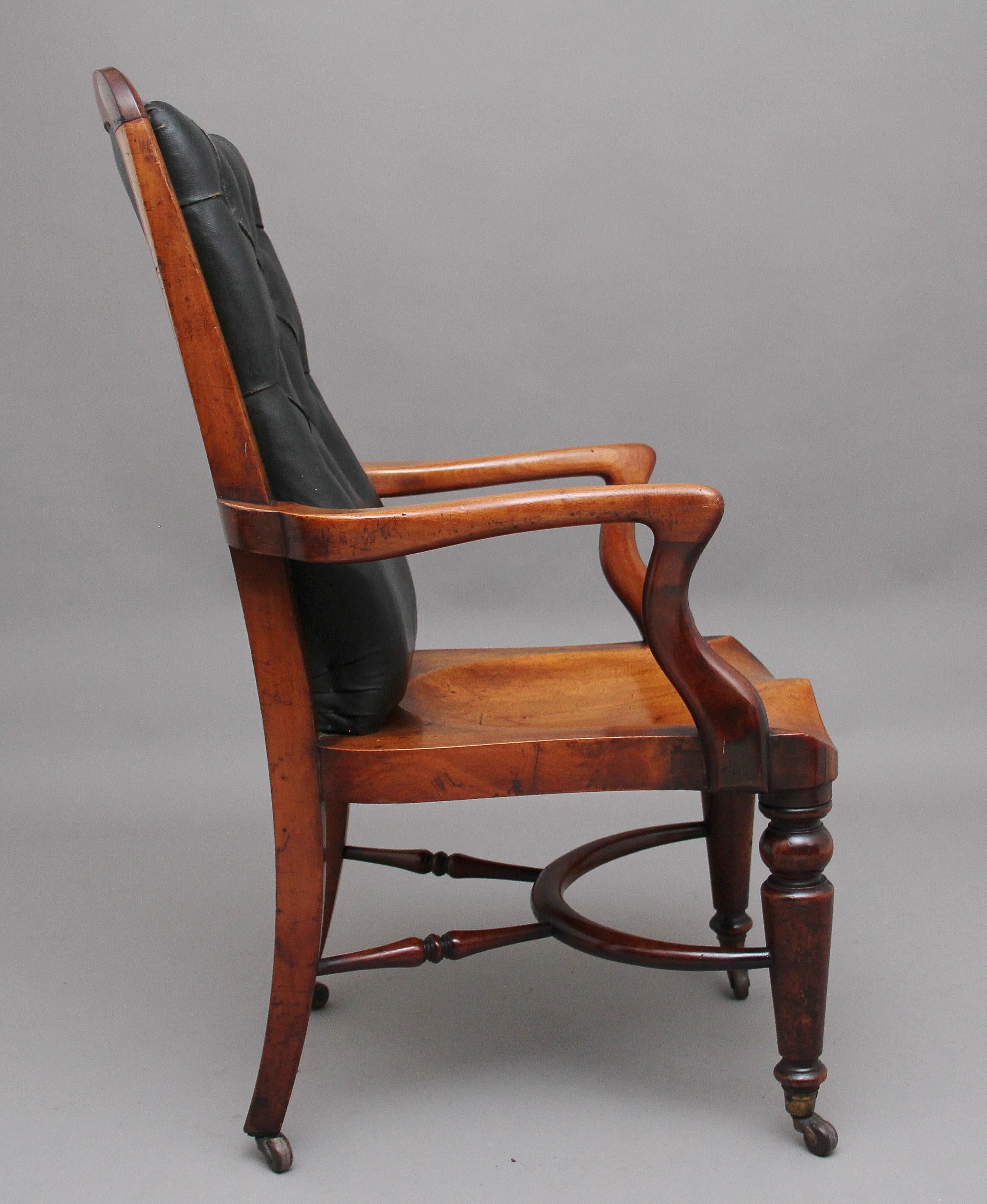 19th century mahogany library / desk chair by Heals of London, having a dark green padded deep buttoned back enclosed in a nice solid mahogany frame, a nice deep saddle seat that is very comfortable to sit at, wonderfully shaped serpentine arms,
