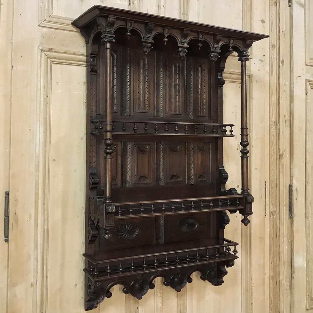 19th century Henri II walnut wall shelf features amazing architectural detail, and hand carved embellishment centered around a theme of fletching, or bird feathers, in stylized form and following the intricate contours of the piece. A colonnade