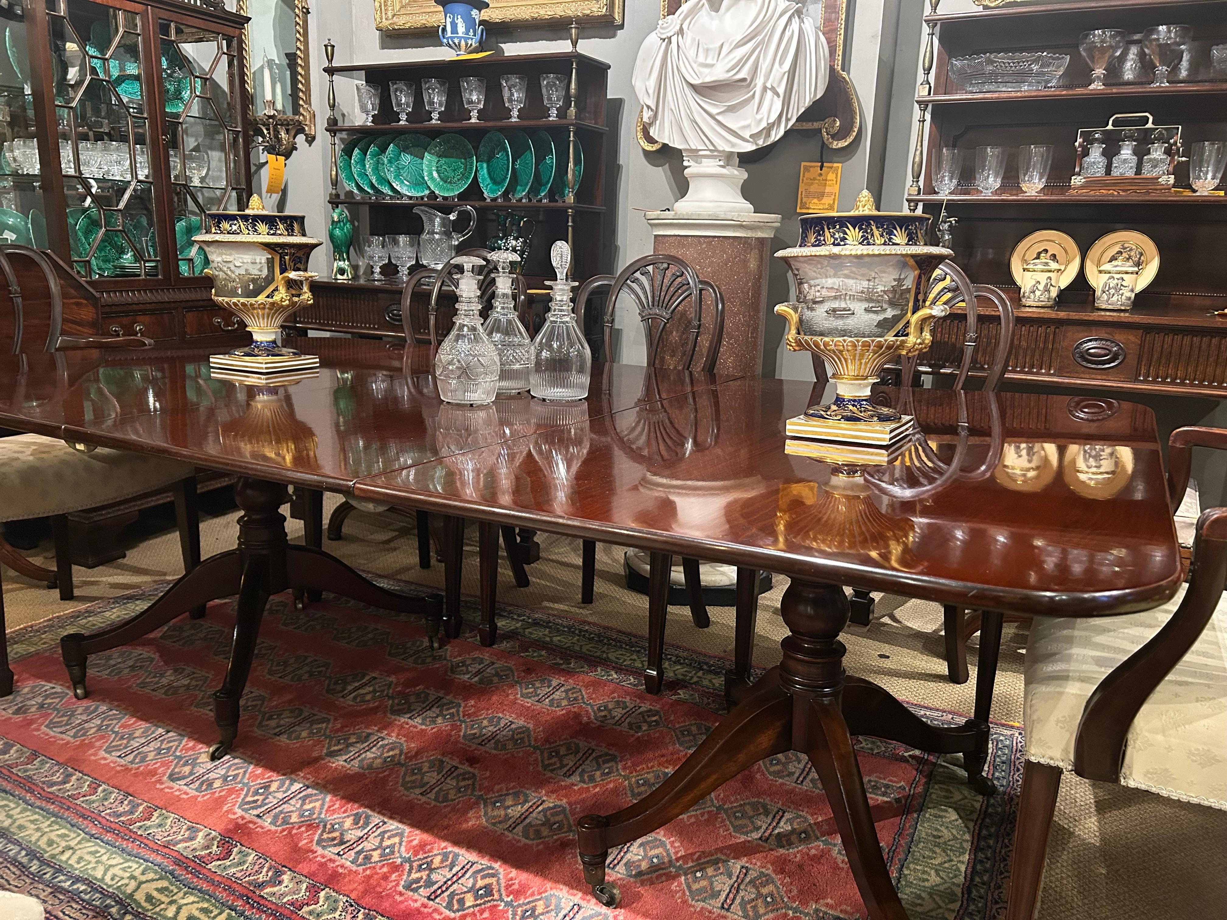 19th Century Georgian mahogany extendable two pod dining table. The moulded top of rectangular form with with one additional leaf raised over two ring turned pods supported by four splayed legs terminating on simple feet supported on brass