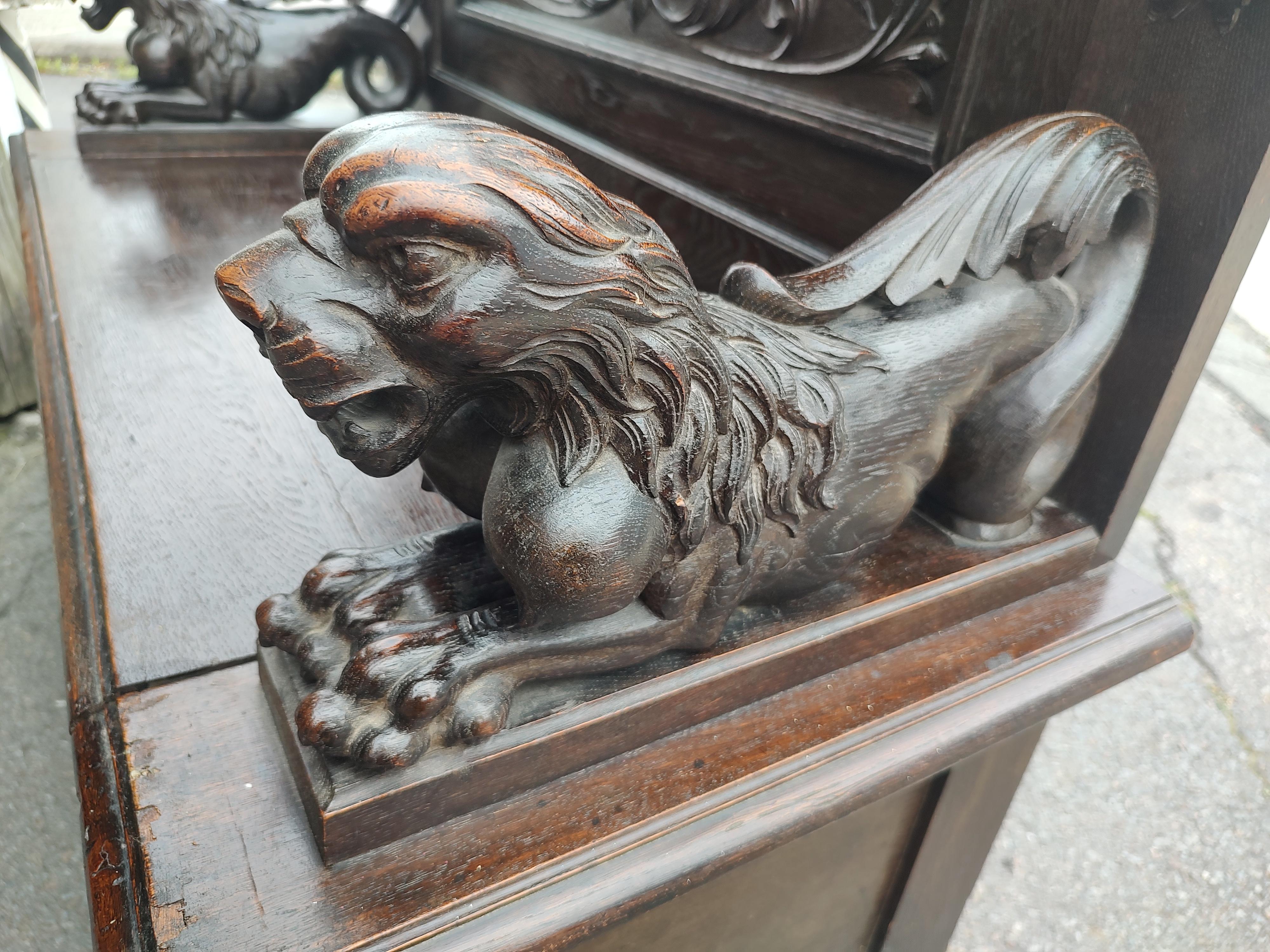 Fantastic highly carved Gothic Oak hall bench with full lions and winged dragons on the back panel. Full body mythic lions make up the armrests while the back panel has swirling dragon heads. Above the arms is carved fruit and the skirt has more