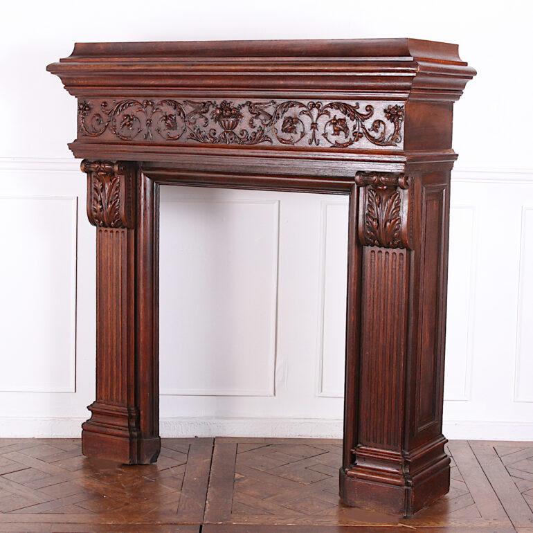 A grand French carved oak Renaissance revivial fire surround or mantlepiece, the molded top above profusely carved frieze with foliate details flanking finely-rendered birds and fruit, raised on fluted pilasters with carved capitals and complex