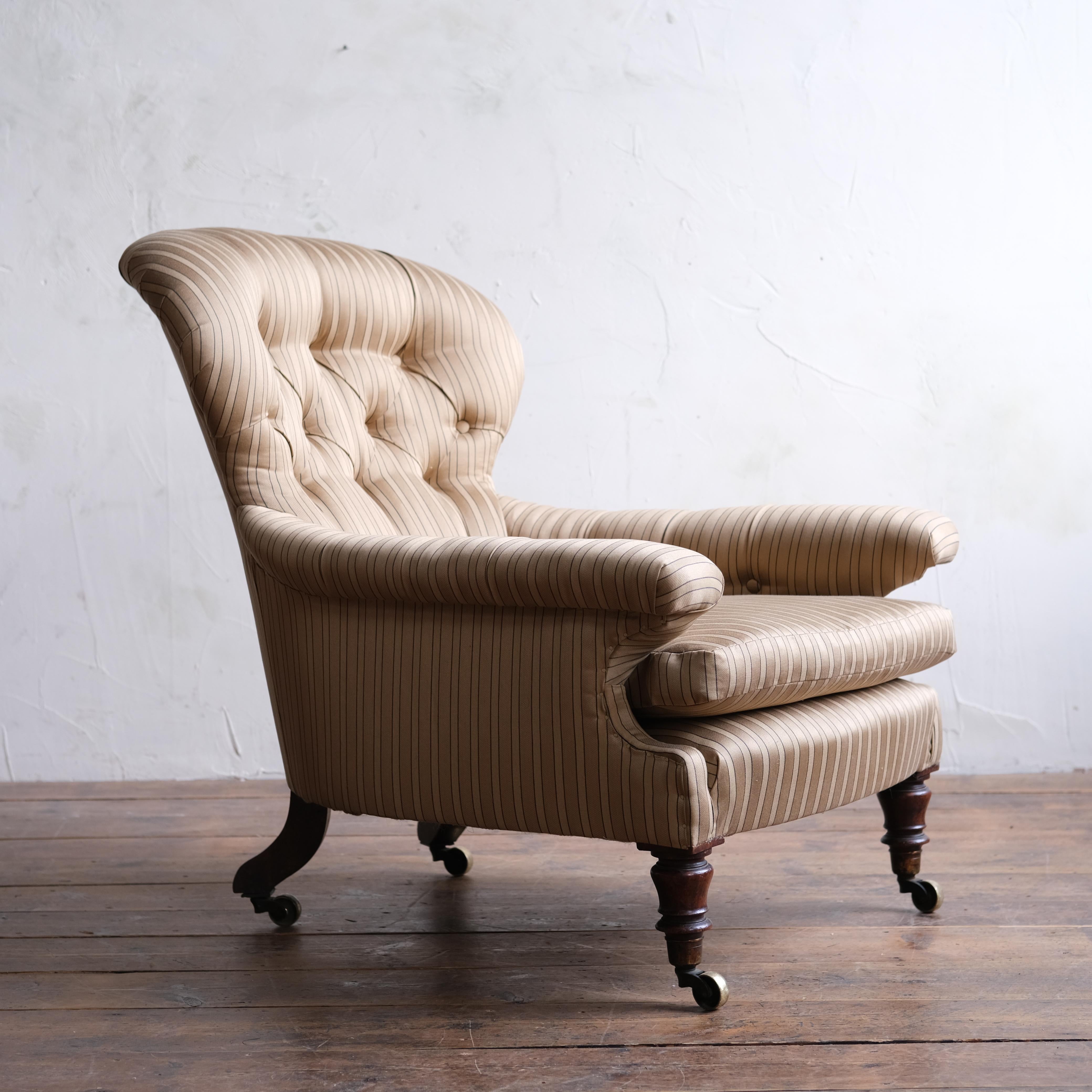 A superb mid-19th century deep seated armchair by Holland & sons. Raised on walnut legs all capped with the original W Hopkins & son's brass casters. Newly upholstered in gold/charcoal Satin stripe by 