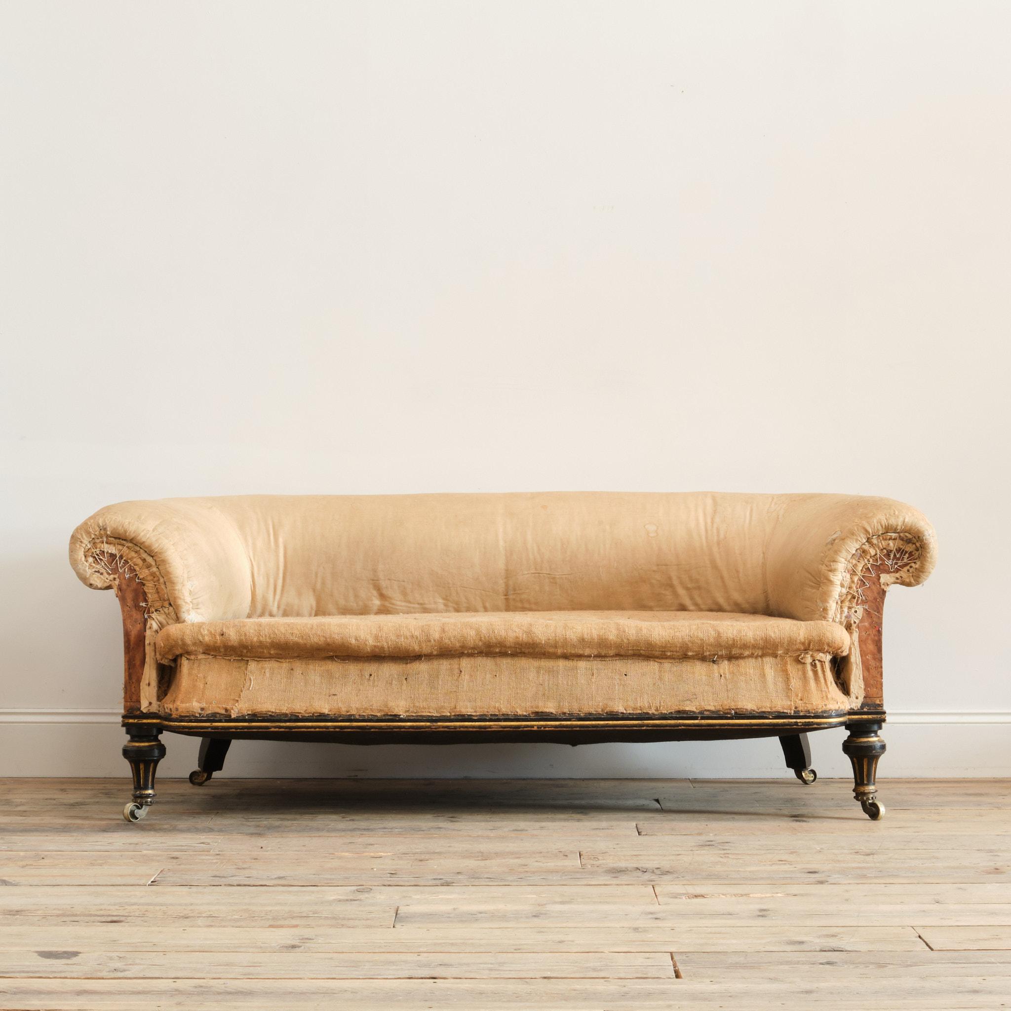 A 19th century country house chesterfield sofa by the renowned Holland & Sons of London. Raised on turned and fluted ebonized and Gilt turned front legs with outward splayed rear legs and all retaining the original brass casters. The left rear leg