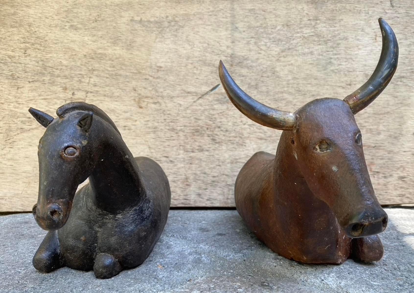 Pair of 19th century Guatemalan carved wooden nativity animals, depicting a recumbent horse and ox. Both figures retain traces of their original polychrome - the horse in deep, worn black and the ox in a warm reddish-brown with applied horn.