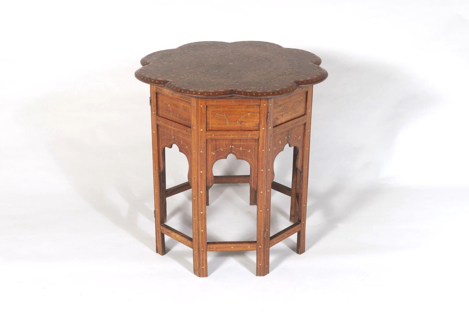 A superbly decorated late 19th Century Hoshiarpur occasional table from British India.  Teak with intense brass inlay filigree top, an unusual flower shape top makes this piece much more desirable, the top also features a fruitwood and ebony chevron