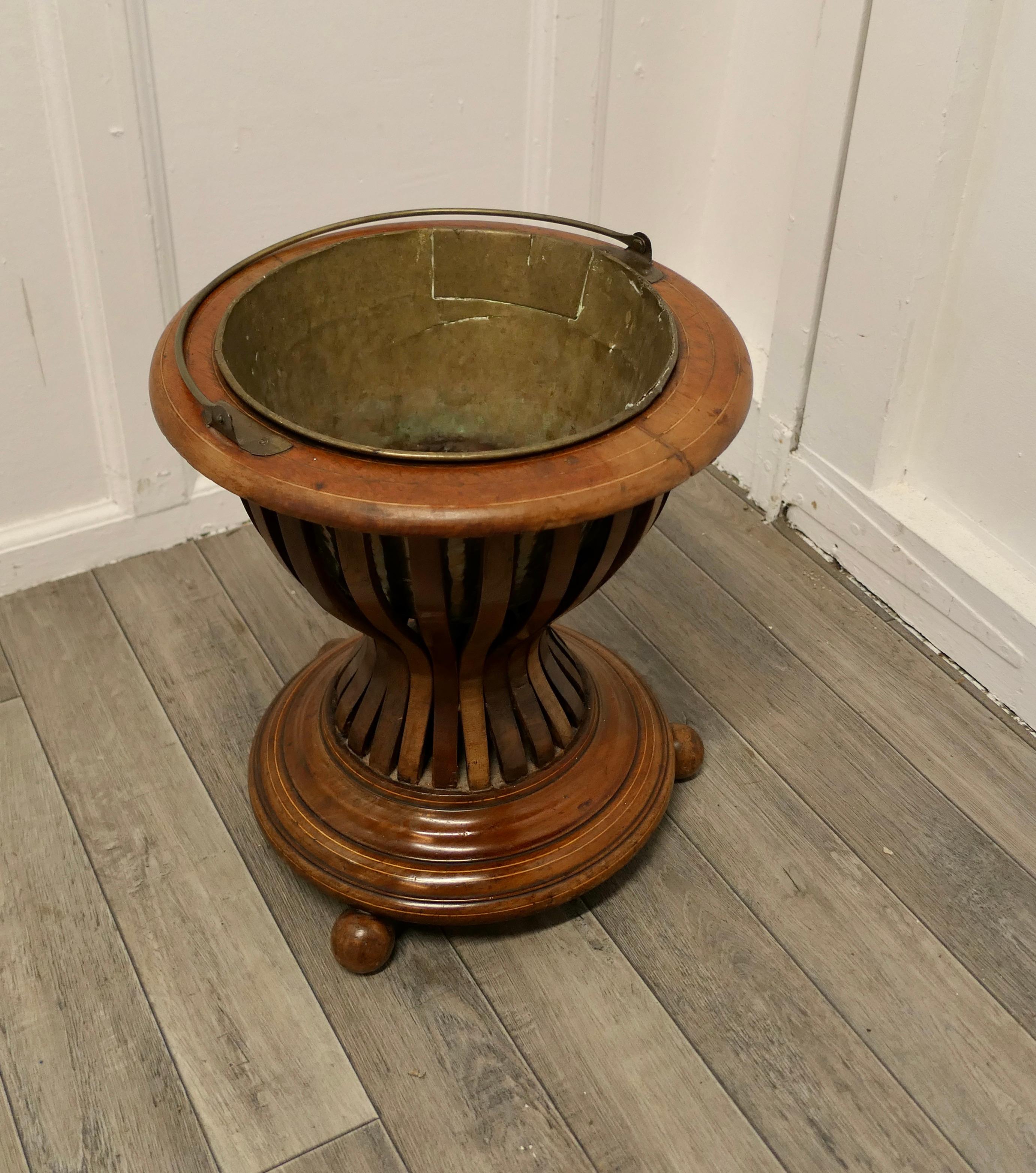 19th century Hourglass peat bucket planter

A very attractive design, the Hourglass shape is made in wood strapping, and the original brass liner is present
The planter sits on turned wooden feet and it has its own handle 
The planter is in good