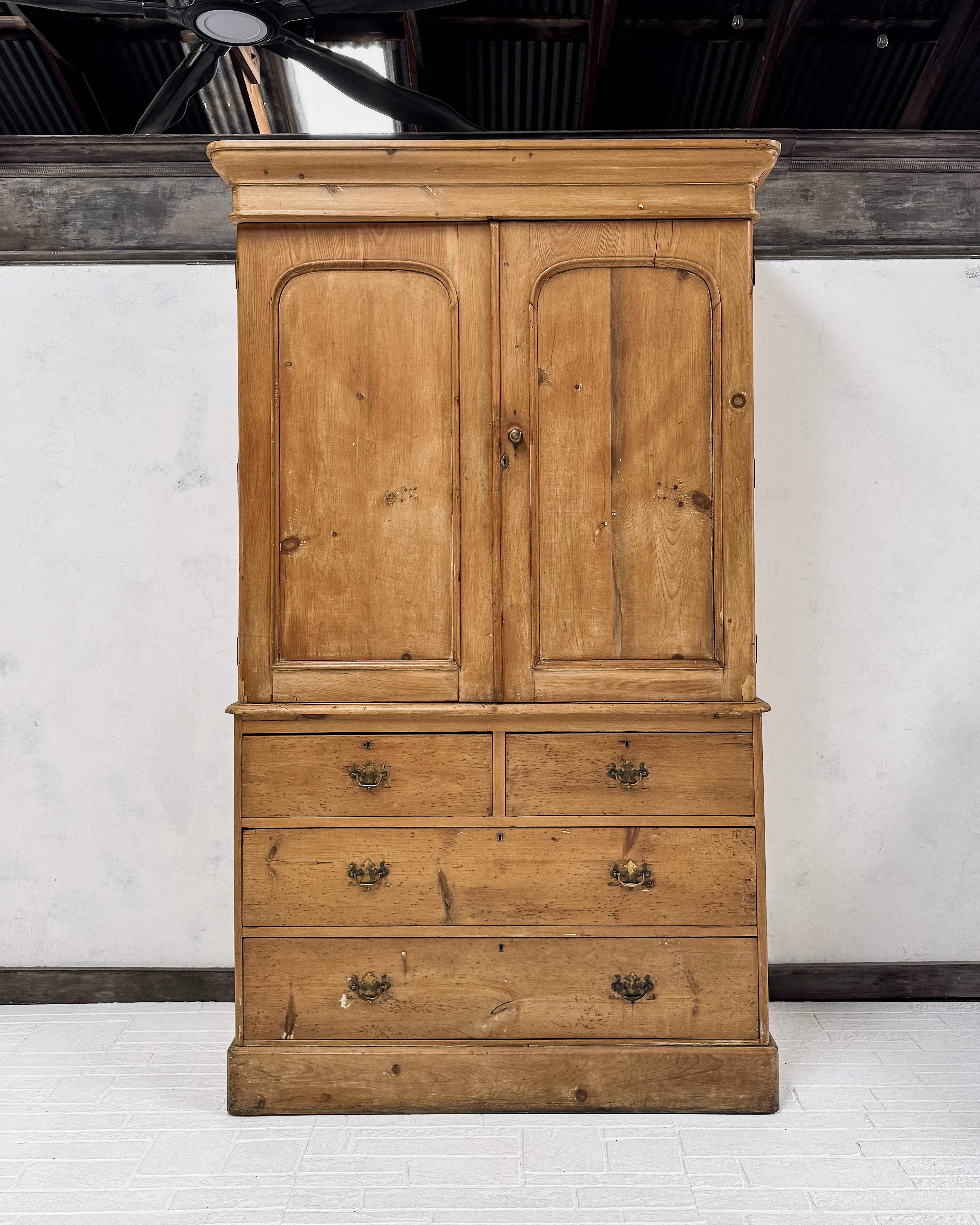 This mid-19th-century English pine housekeeper’s cupboard balances function and understated craftsmanship. Found in England, this two-part piece features a distinctive arched panel design on the upper doors, accented by a brass mushroom knob.