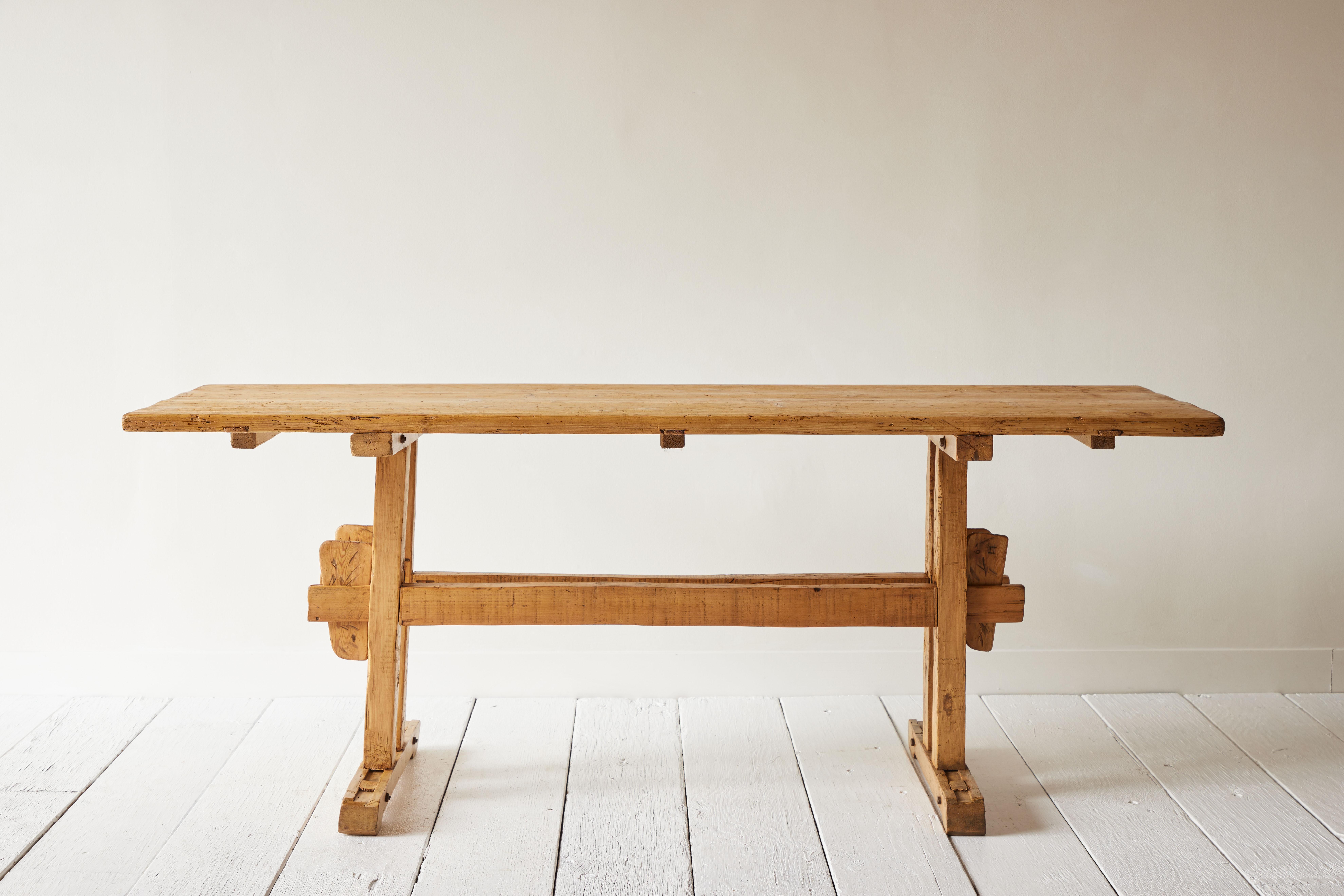 Trestle tables such as this were used during harvest season to feed the additional farm workers on hand to bring in the crops. The trestle base made it easy to take apart, transport and assemble quickly and easily. This pine trestle table is in