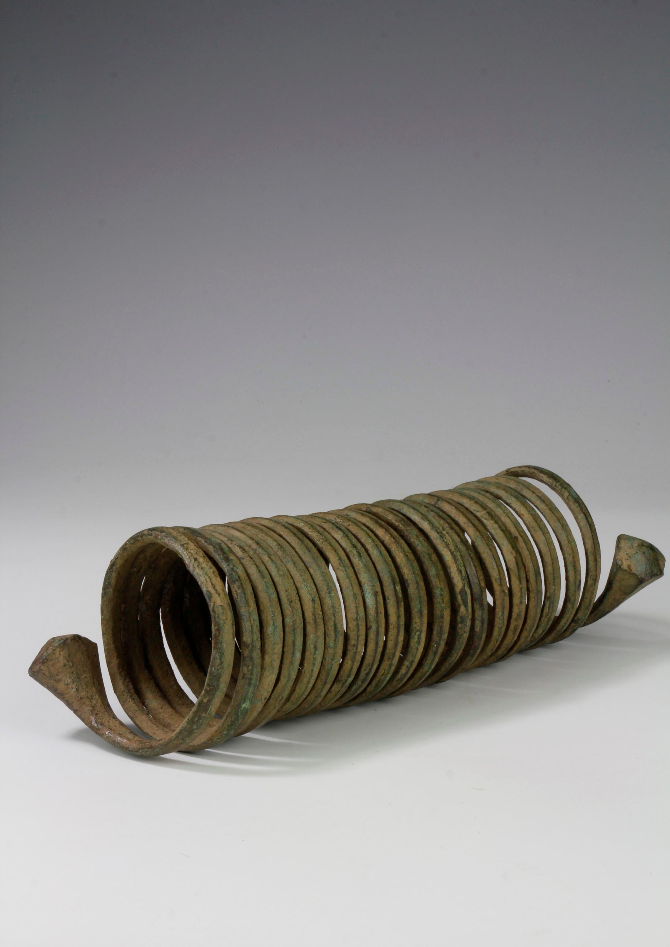 Dieser Armschmuck einer Igbo-Frau aus Nigeria, der in einer schönen gewundenen Form gegossen wurde, diente auch als Zahlungsmittel. Dieses Stück aus dem 19. Jahrhundert hat eine schöne grüne Grünspan-Patina auf der Oberfläche entwickelt.

-Ex