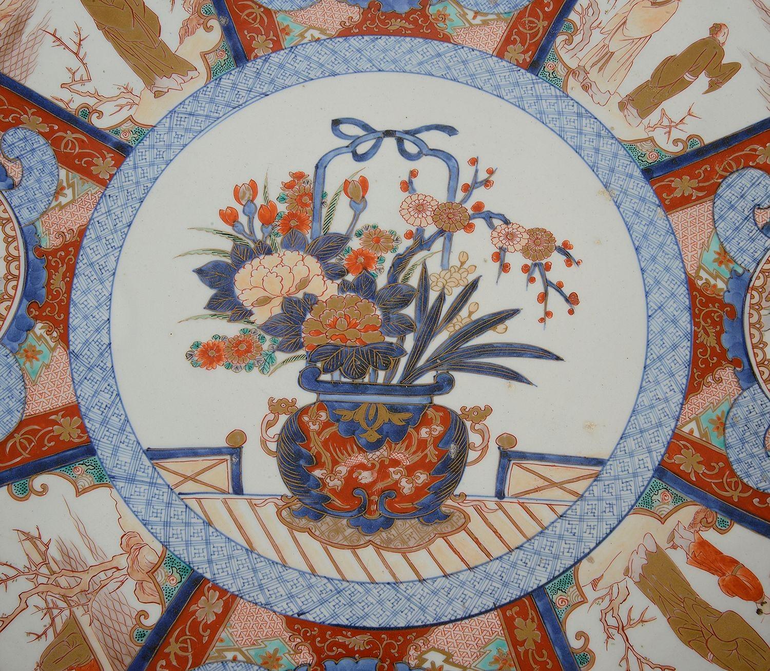 A very good quality late 19th Century Japanese Imari charger, having wonderful bold colouring, with eight inset panels depicting various courtiers and scholars, surrounding the central scene with a jardiniere full of exotic flowers. The boarders