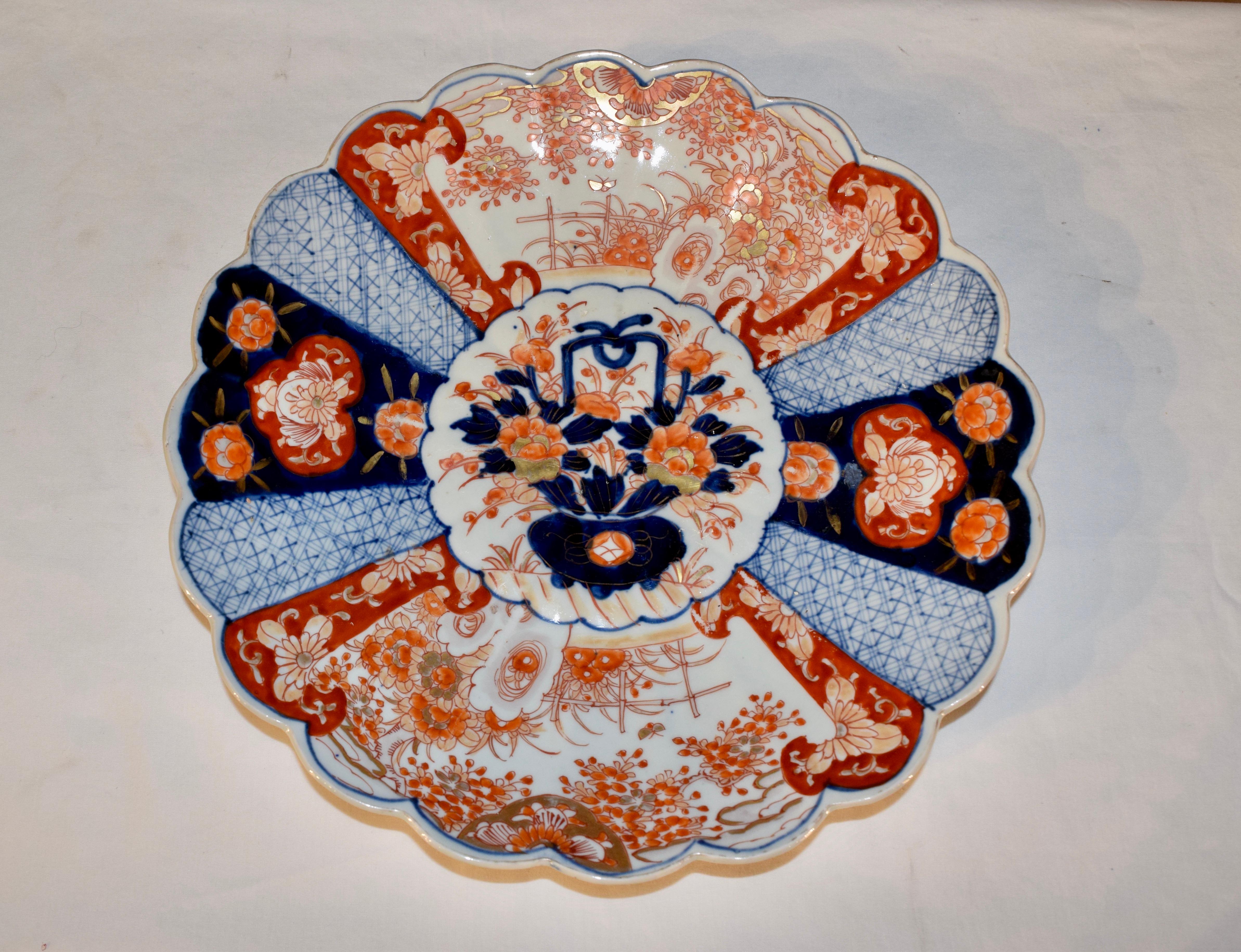 19th century Imari charger from Japan with a central medallion containing a hand polychromed flower basket, surrounded by a fan design, all containing patterns alternating with florals and garden scenes.