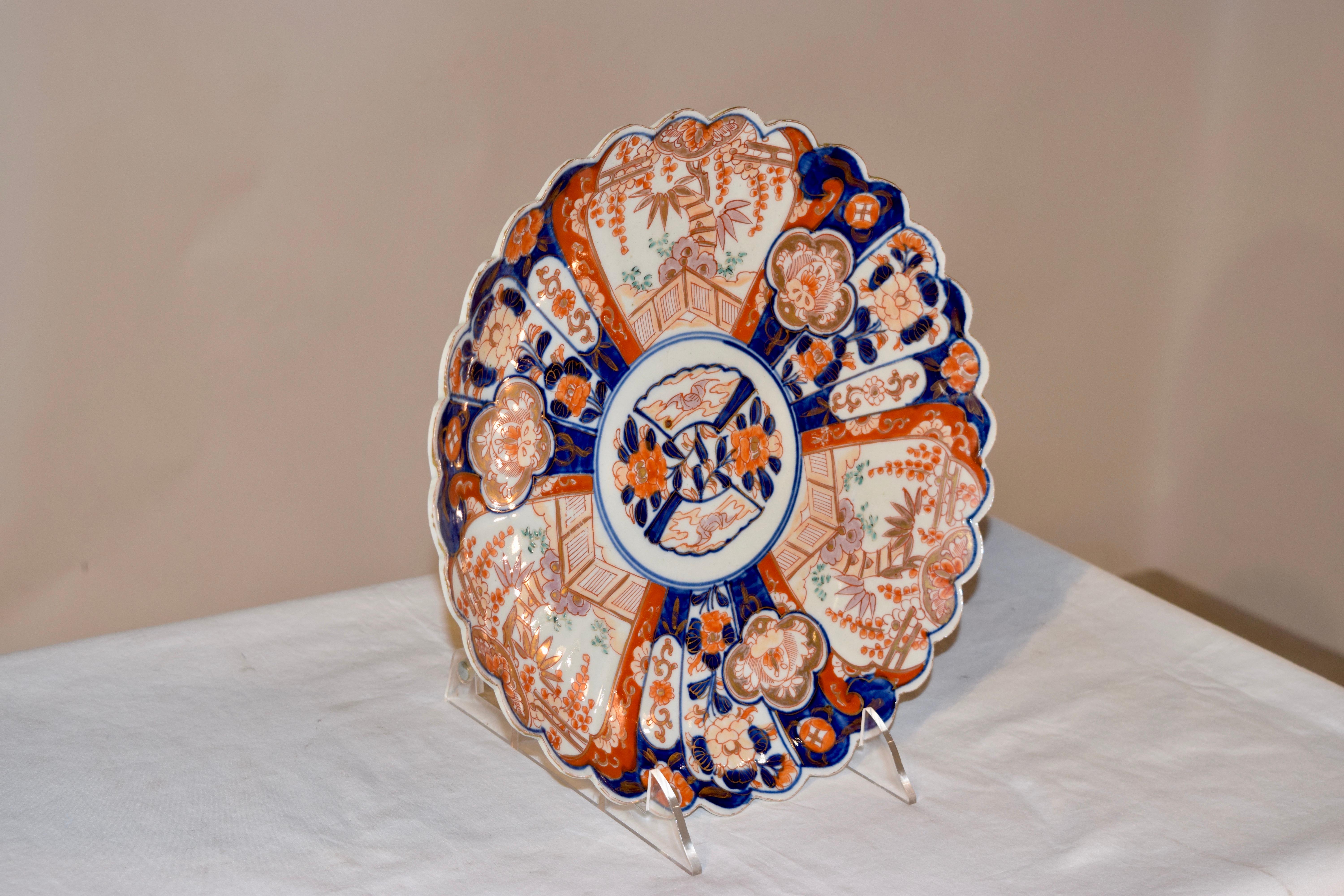 19th century Imari charger from Japan with a central medallion containing a hand polychromed floral design, surrounded by a fan design, all containing patterns alternating with florals and garden scenes.