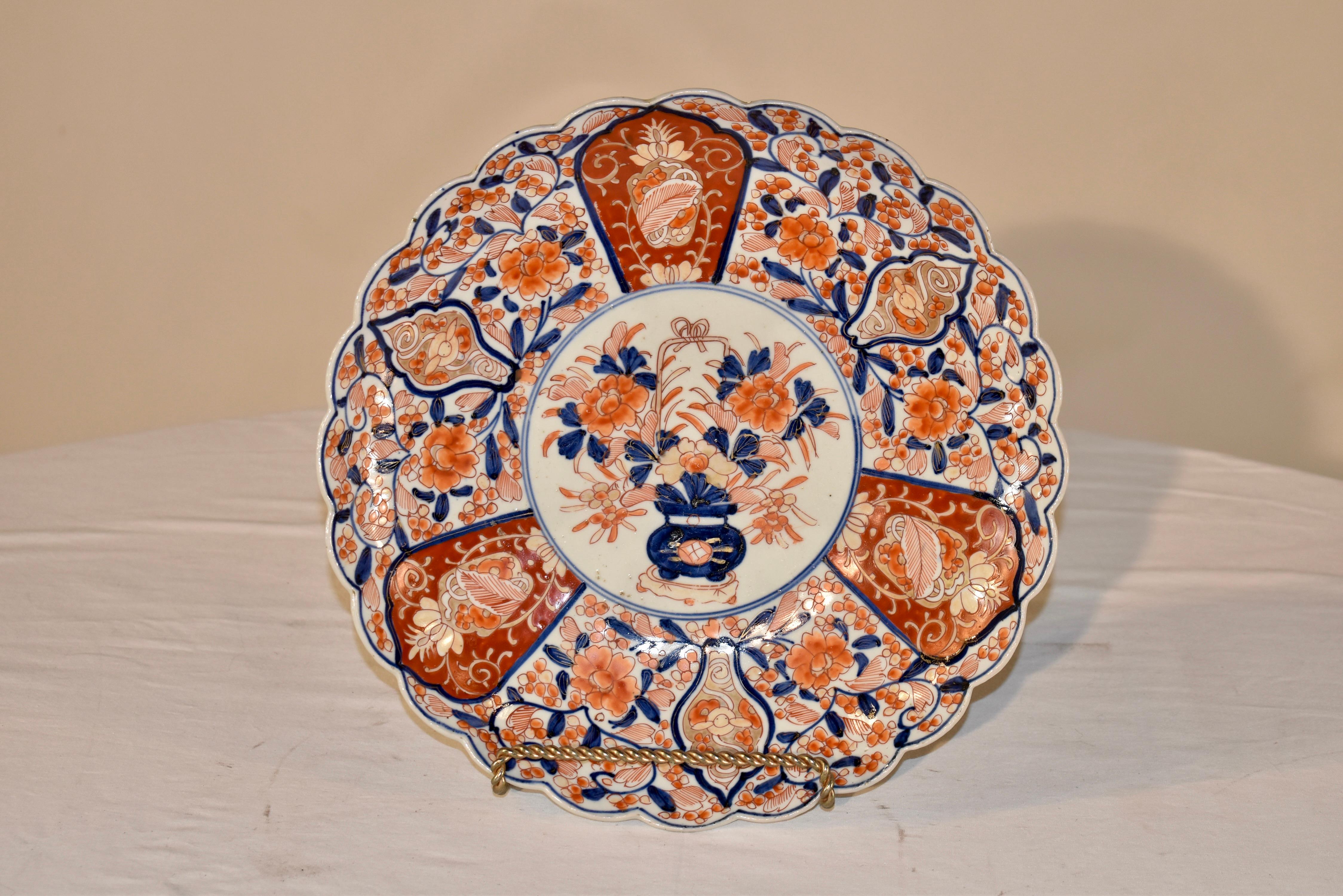Late 19th century Imari large plate with a lovely scalloped edge. The central medallion is on an ivory colored background with a vase of hand painted florals, surrounded by three blades of burnt orange color with hand painted decorations, flanked by