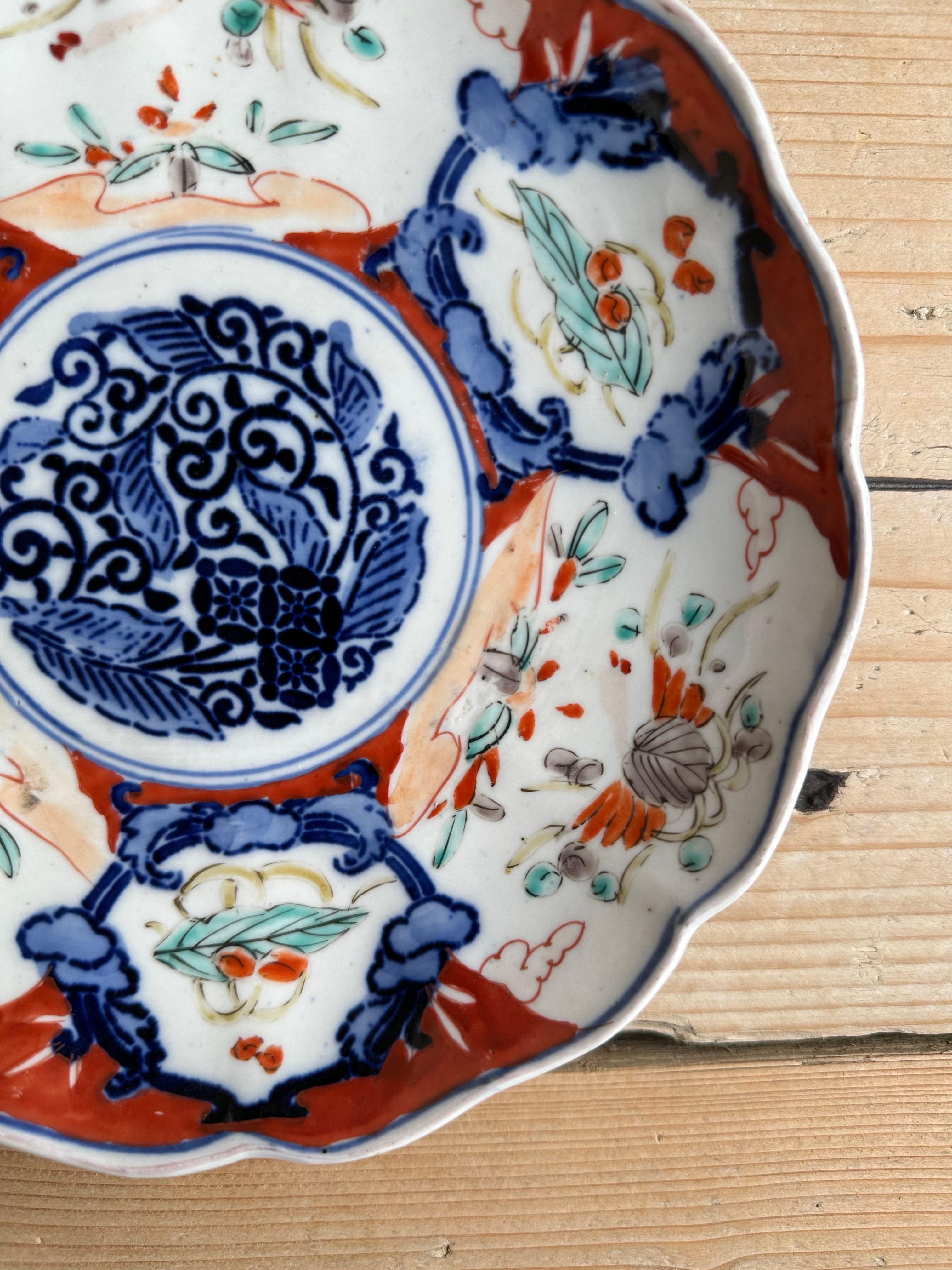 L'immagine mostra un pezzo di Imari ware, uno stile di porcellana giapponese prodotto ad Arita ed esportato dal porto di Imari. Questo tipo di porcellana è noto per i suoi colori vivaci, che in genere includono il rosso ferro, il blu sottosmalto e