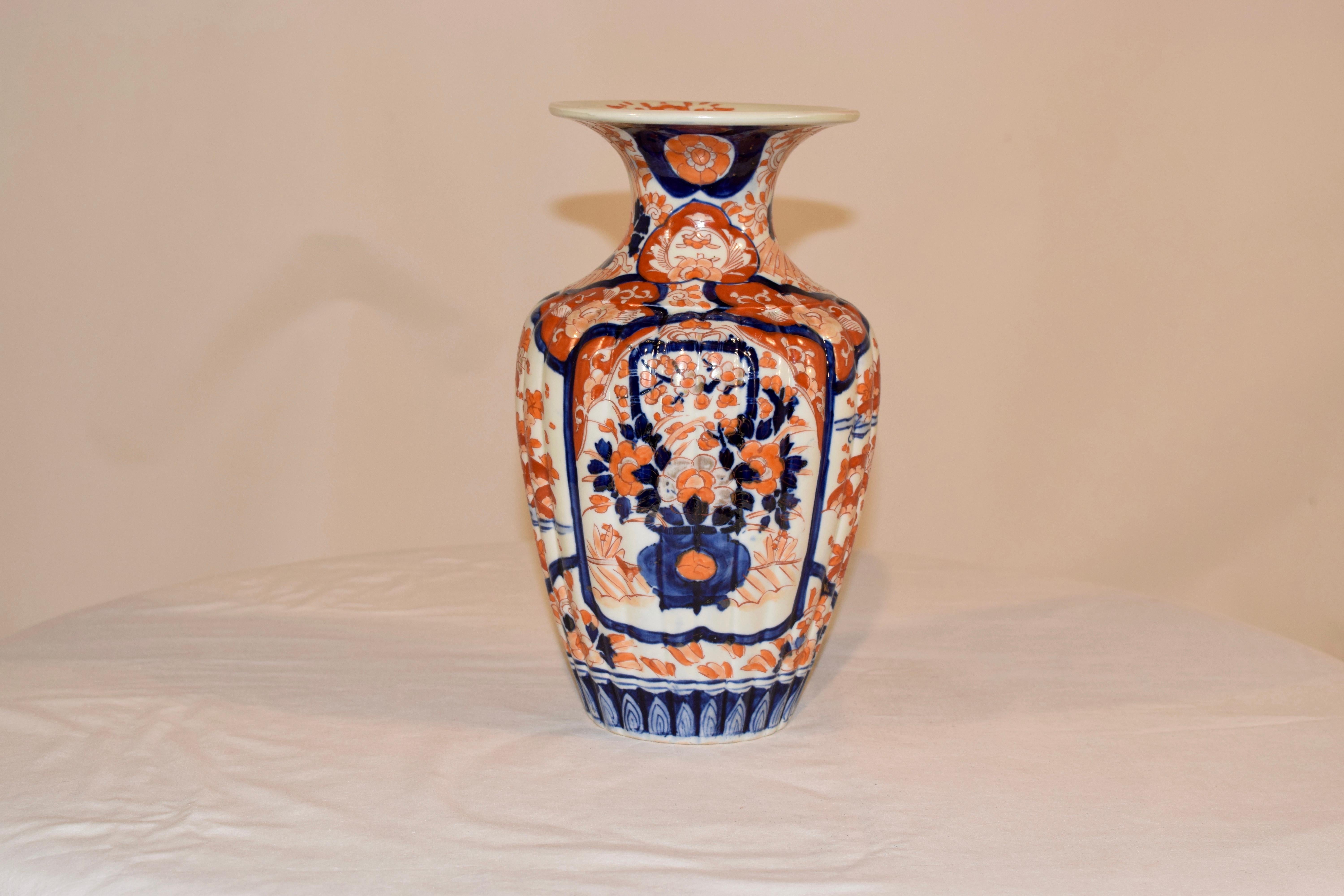 19th century Imari vase with two central medallions, one on each side, with beautiful hand painted decorations of garden scenes with urns and flowers, and two sides decorated with hand painted garden scenes. The vase itself is ribbed, which gives it