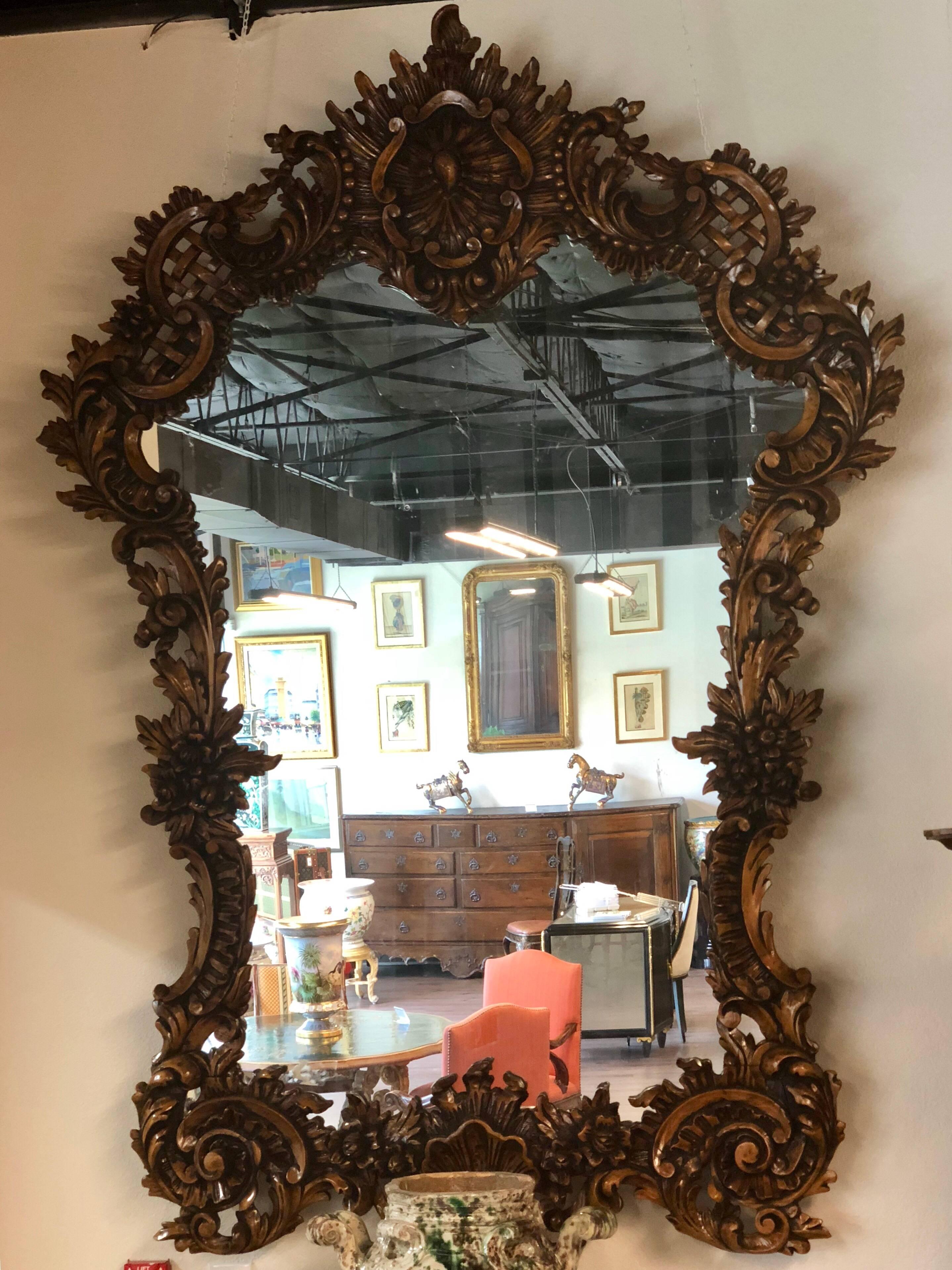 This magnificent ballroom mirror is impressive in its size and deeply carved decoration in the typical Flemish style of the mid-19th century Dutch Baroque period. Distinct wood grain occasionally peeks through the coarsely hewn oak wood frame to
