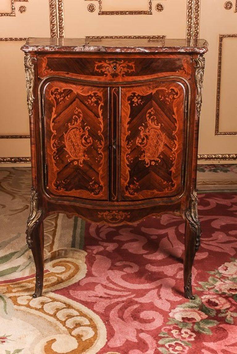 Bois-Satiné-veneer, all-round covering mirror veneer and marquetry on solid conifers. With finely chiselled, highly decorative, perforated rocaille, fire-gilded bronze fittings. Two-legged, singular corpus on slanting, curly legs ending in sabot,