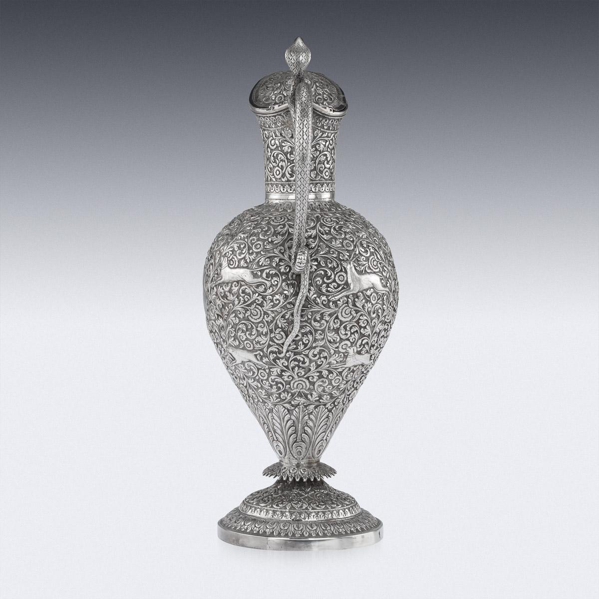 Antique late 19th century Indian Colonial solid silver ewer, inverted baluster body resting on a circular foot, applied with a scrolled cobra handle and hinged lid. The piece is profusely and beautifully chased in typically Cutch style depicting