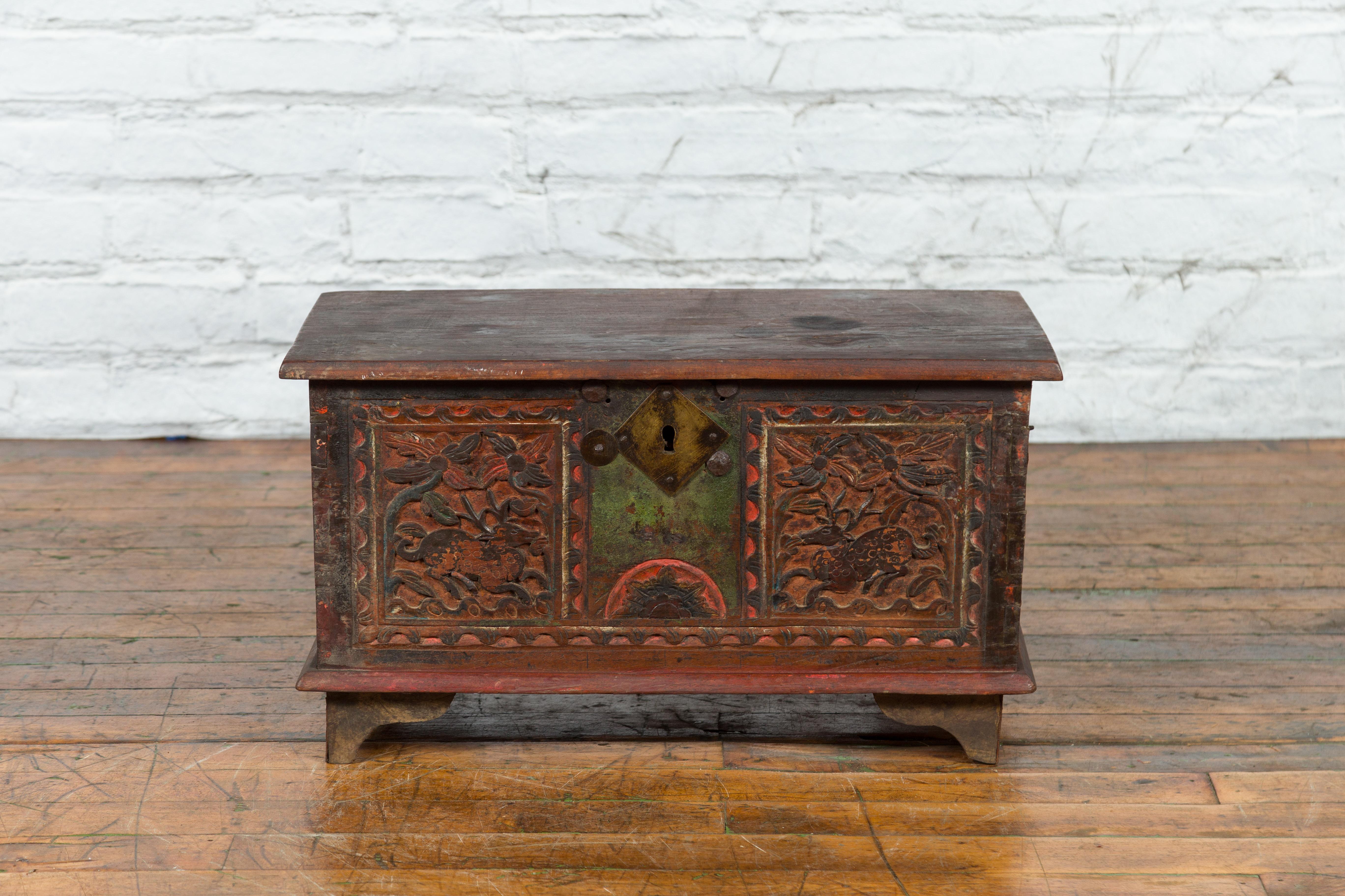 An Indian green and red polychromed wooden trunk from the 19th century, with hand-carved and hand-painted floral and deer motifs. Created in India during the 19th century, this wooden trunk features a rectangular lid that opens up to reveal a rustic