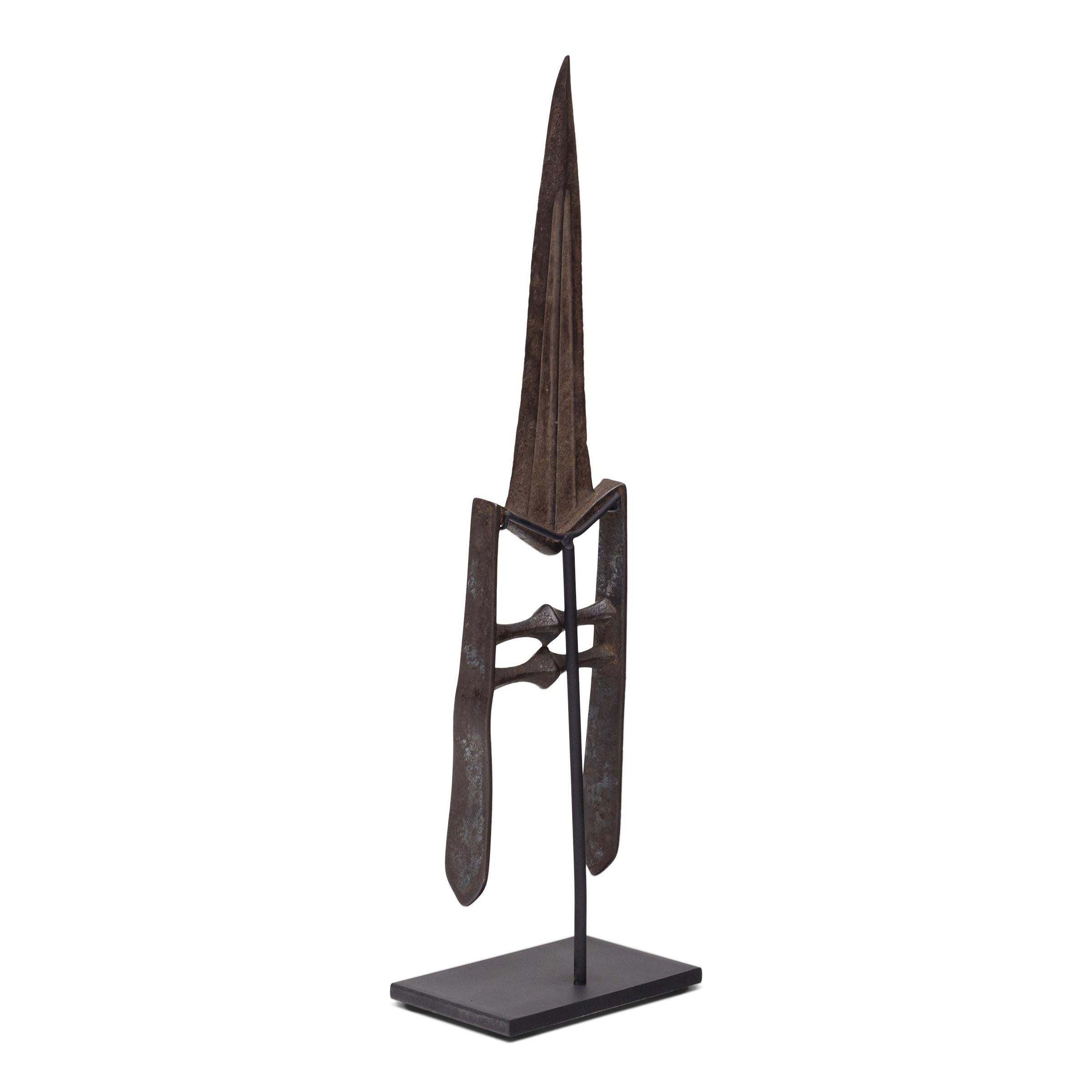 This unusual weapon is a cast iron Indian push dagger, known as katar or katara. Dated to the late 19th century, the katar features a hand-grip of two horizontal bars and a broad, triangular blade ideal for piercing through armor or chainmail. An