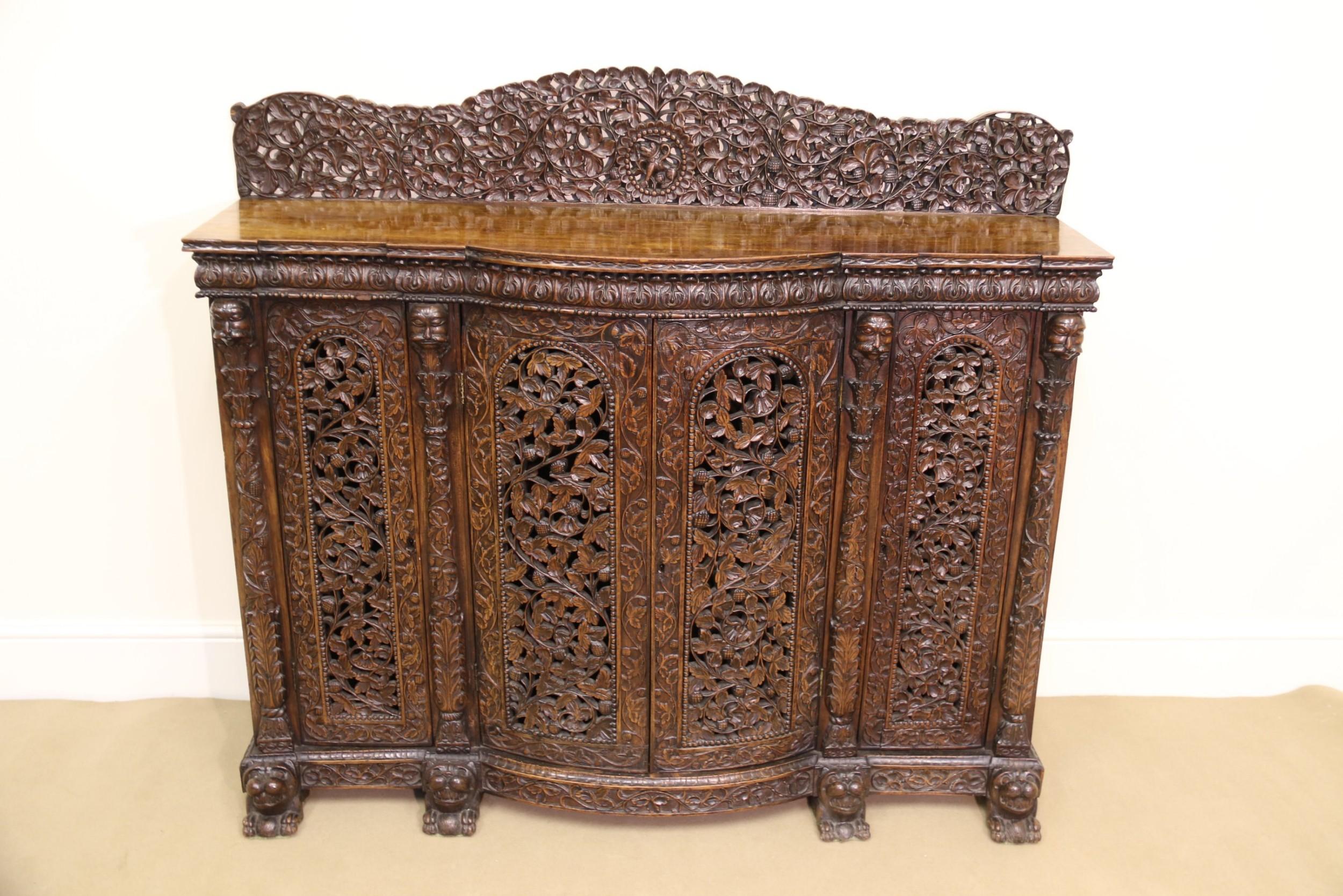 This highly decorative and impressive 19th century Indian carved padauk wood cabinet is profusely carved with fine foliate detail throughout.
The figured top has a raised decorative back panel. Below there is a shaped frieze with acanthus leaf