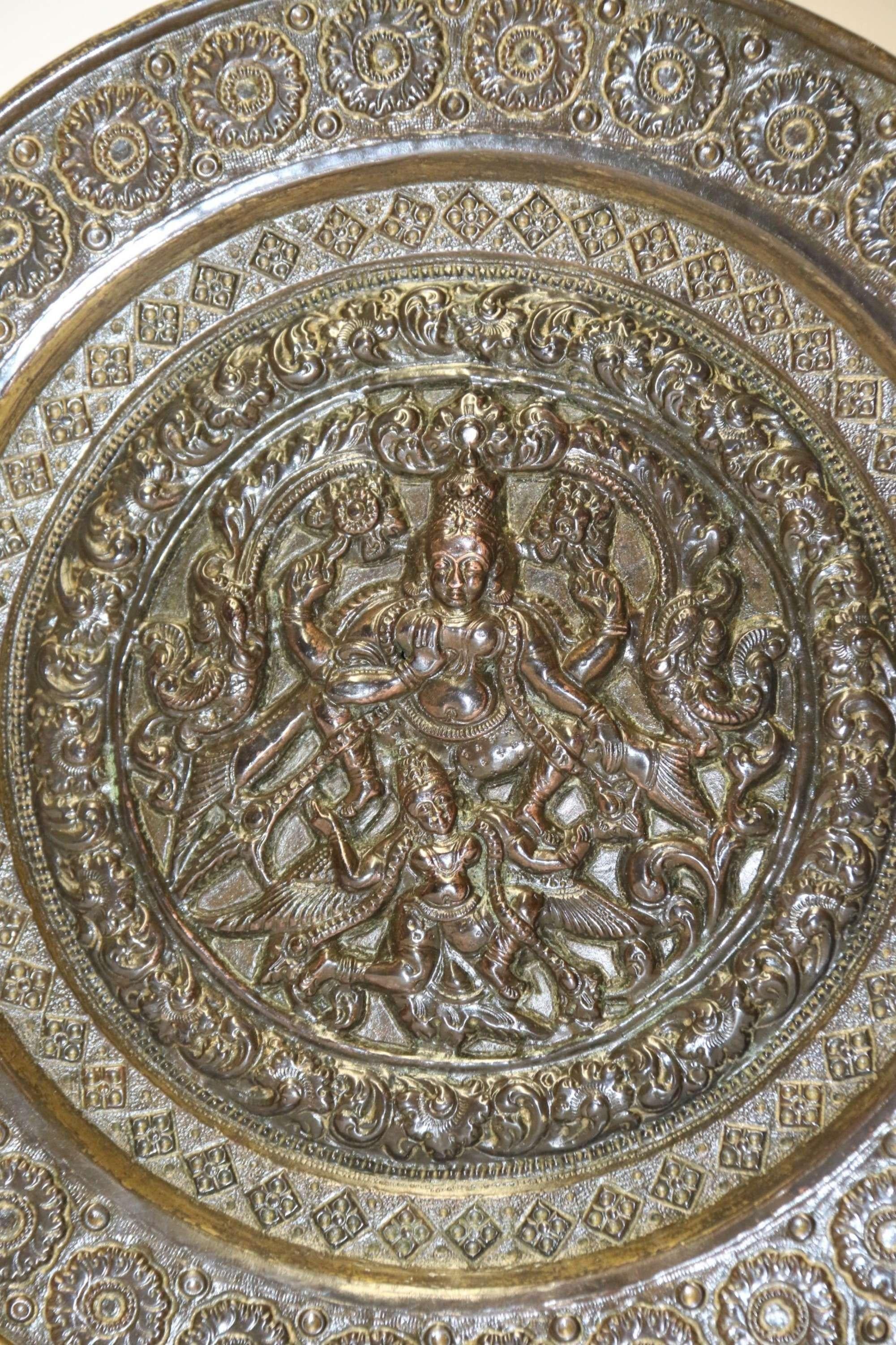A.C.I.C. Indian Raj Period Plaque

Cette plaque en cuivre et en laiton de la période du Raj indien, finement travaillée et ciselée, présente un panneau central complexe représentant Nataraga, le dieu de la danse, accompagné d'oiseaux exotiques. Le