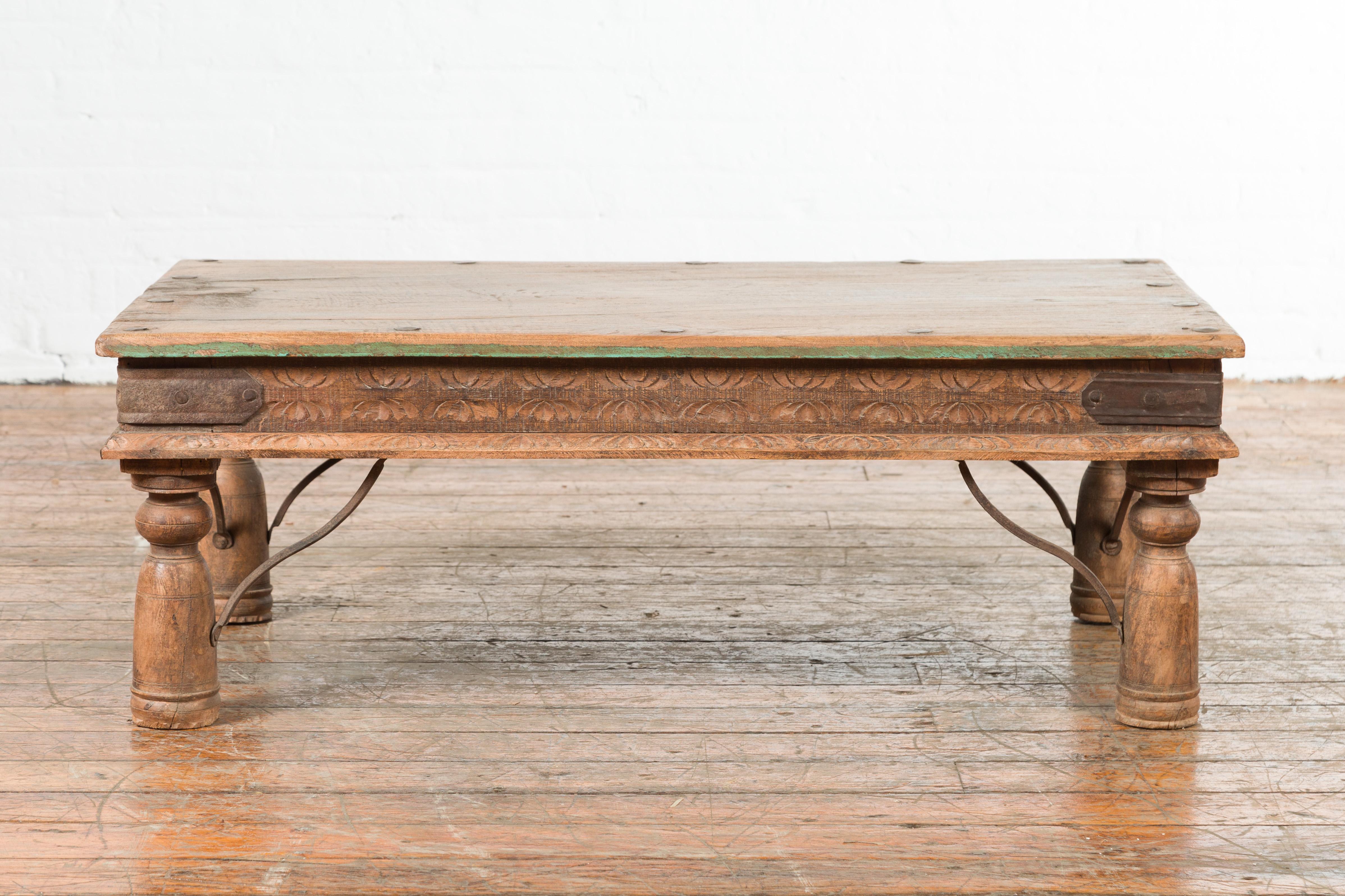 An Indian antique small coffee table from the 19th century, with iron accents, green paint and carved apron. Created in India during the 19th century, this coffee table features a rectangular single planked top with iron studs and traces of green