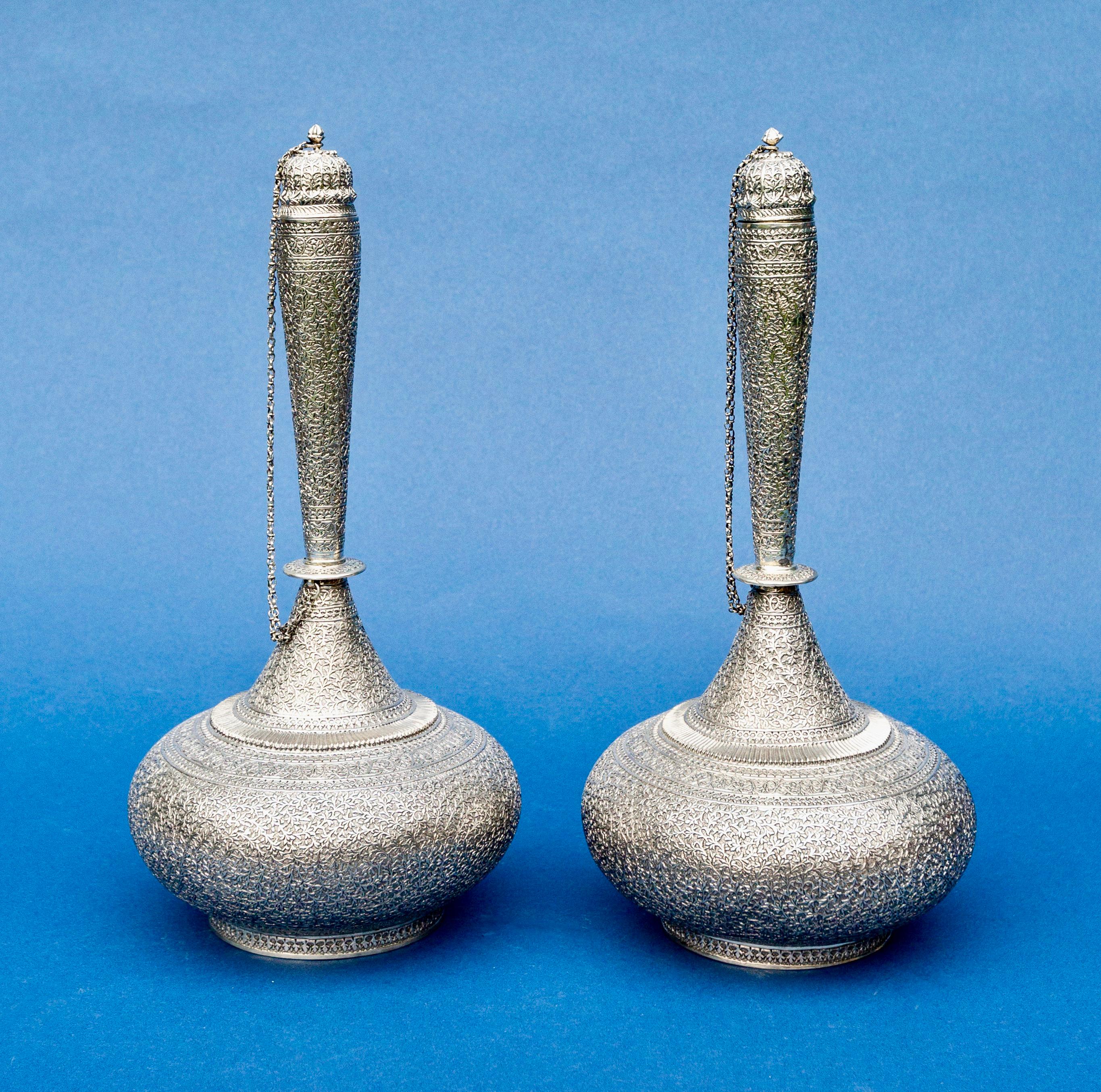 Pair of Indian silver rosewater bottles each with chained domed cover.