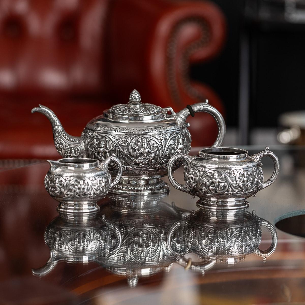 Antique late 19th Century Indian Colonial solid silver three-piece tea set, comprising of a teapot, sugar bowl, and cream jug, each bulbous body is profusely and beautifully repousse' decorated with deities surrounded by large scrolling foliage,