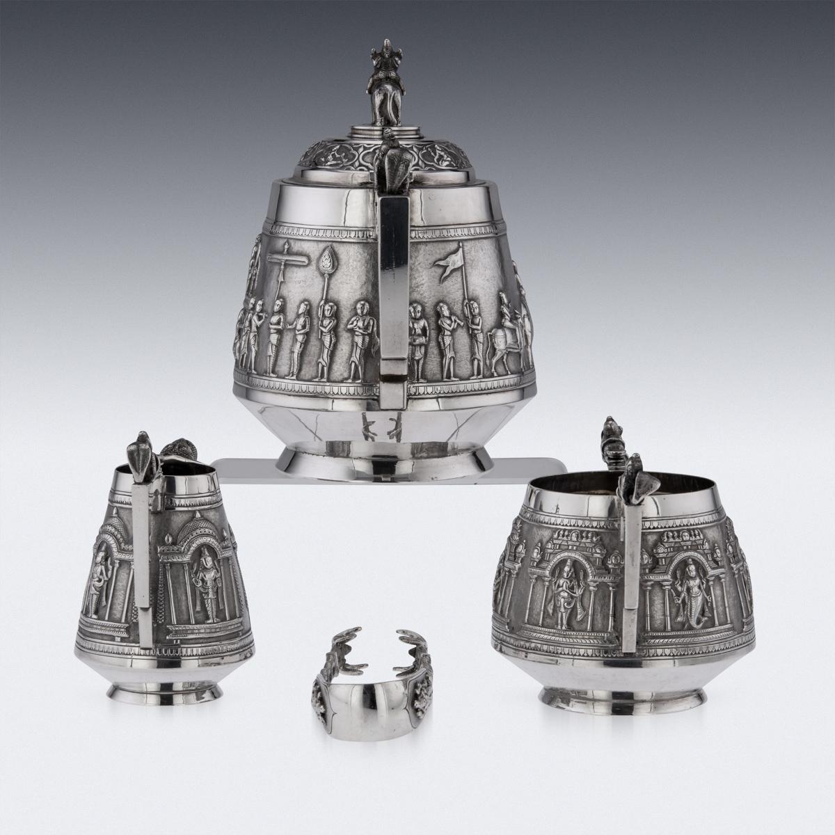Antique 19th Century Indian Colonial solid silver four-piece tea set, comprising of teapot, sugar bowl, cream jug and tongs, each straight tapered body is profusely and beautifully repousse' decorated with a religious processions with men carrying