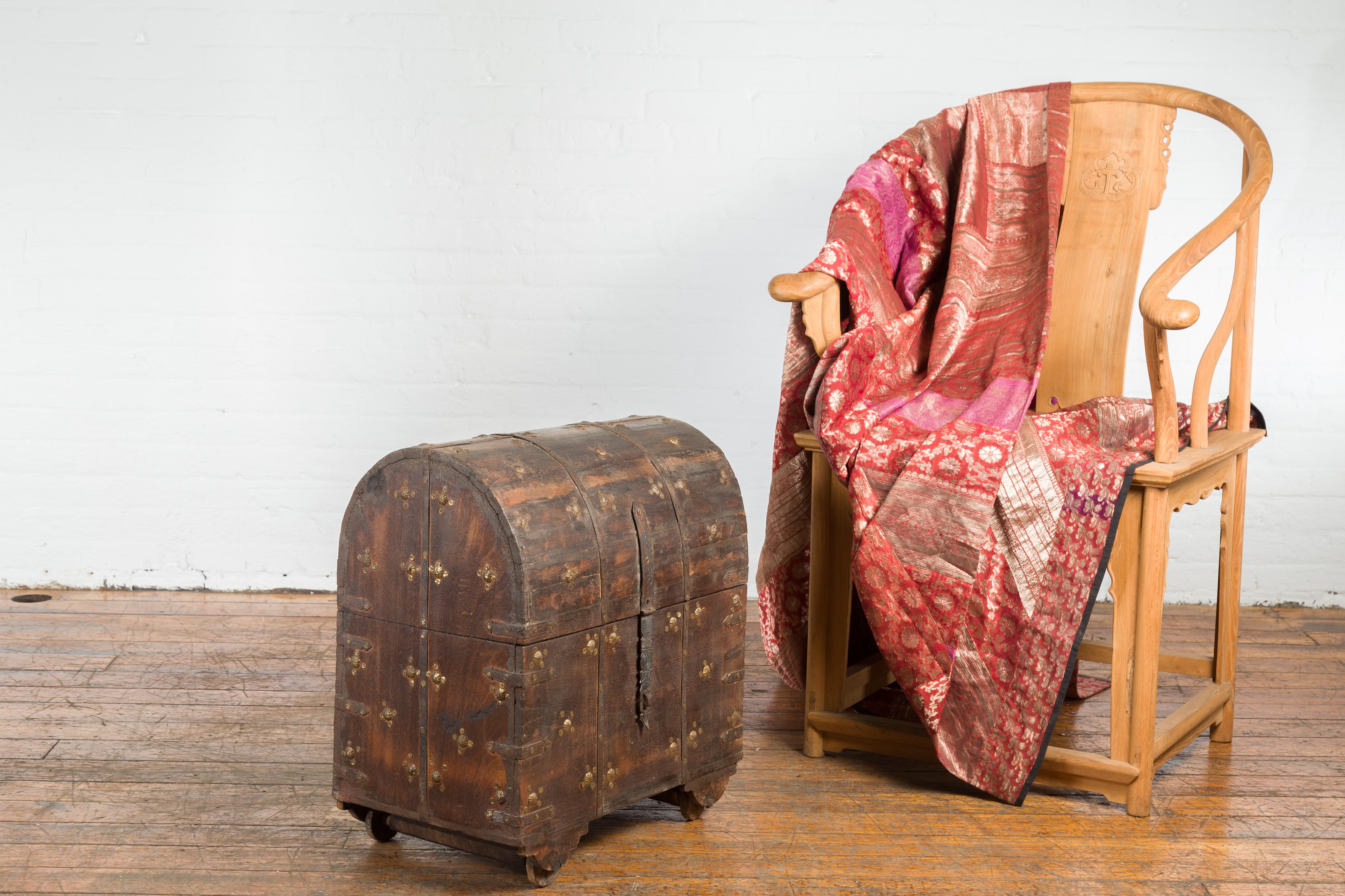 Indian antique wooden treasure chest from the 19th century, with dome top, metal accents and petite wheels. Created in India during the 19th century, this treasure chest captures our attention with its distressed wooden structure accented with