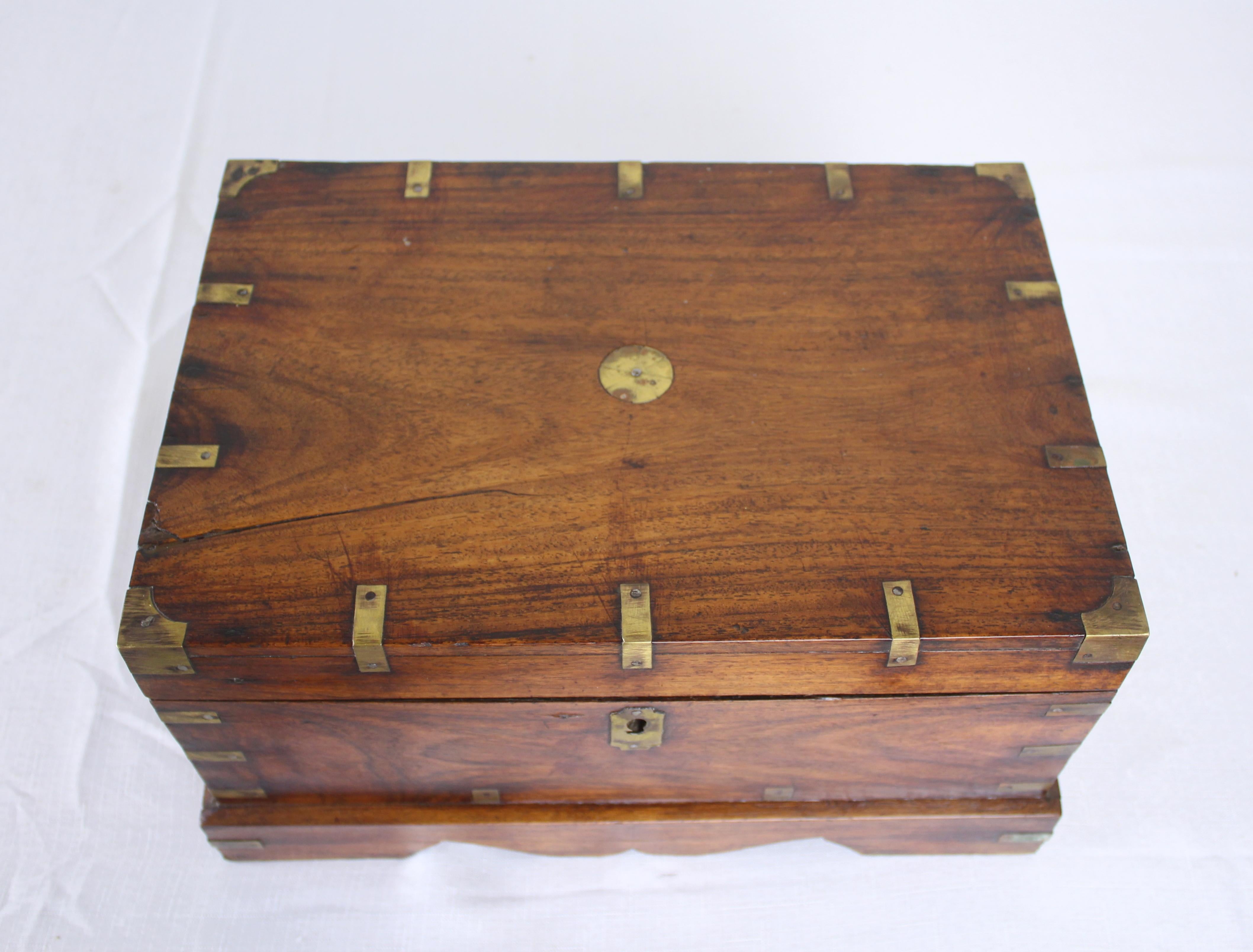 An Indo European storage box in teak with brass exterior supports and shaped base. Inside houses six individual compartments with their won lids. In overall good condition with a split on the lid (as shown).