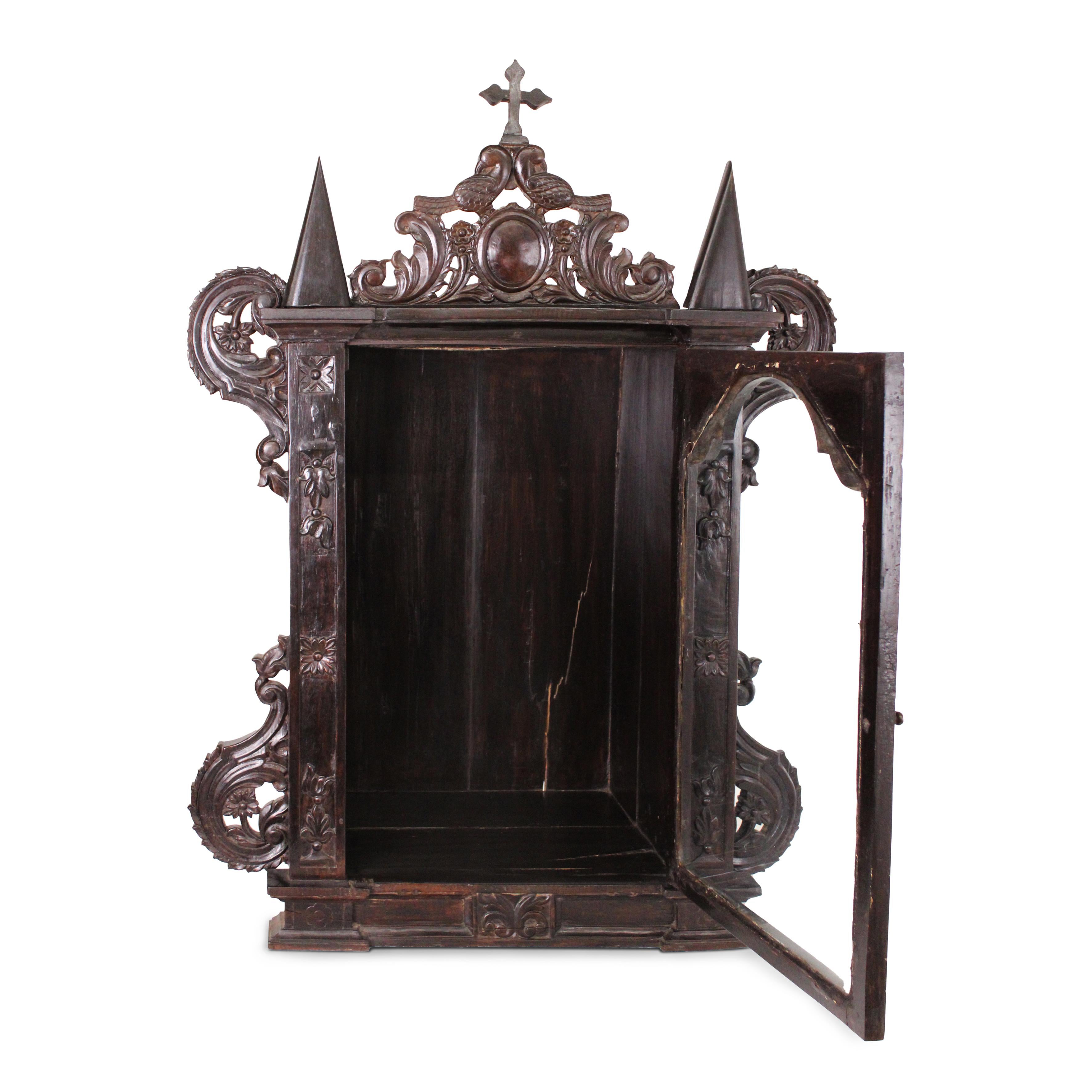 This 19th-century Indo-Portuguese tabernacle is masterfully crafted from rich rosewood and crowned with a beautifully carved cross at the pinnacle. This exceptional piece exemplifies the harmonious blend of European ecclesiastical design and Indian