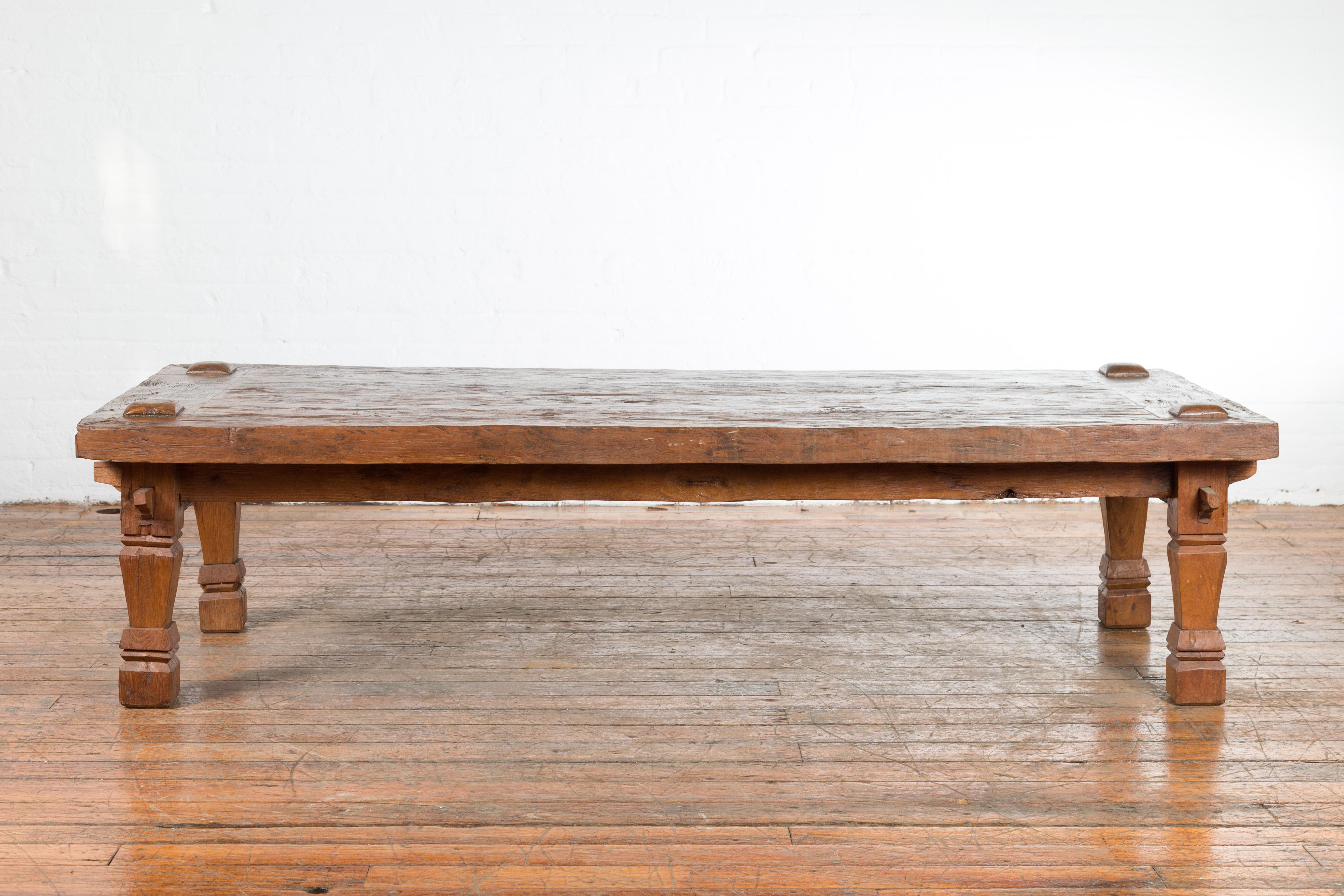 A 19th century Indonesian wooden coffee table from Madura with carved legs and raised joints. Created in Madura off of the northeastern coast of Java during the 19th century, this wooden coffee table features a nicely rustic rectangular top with