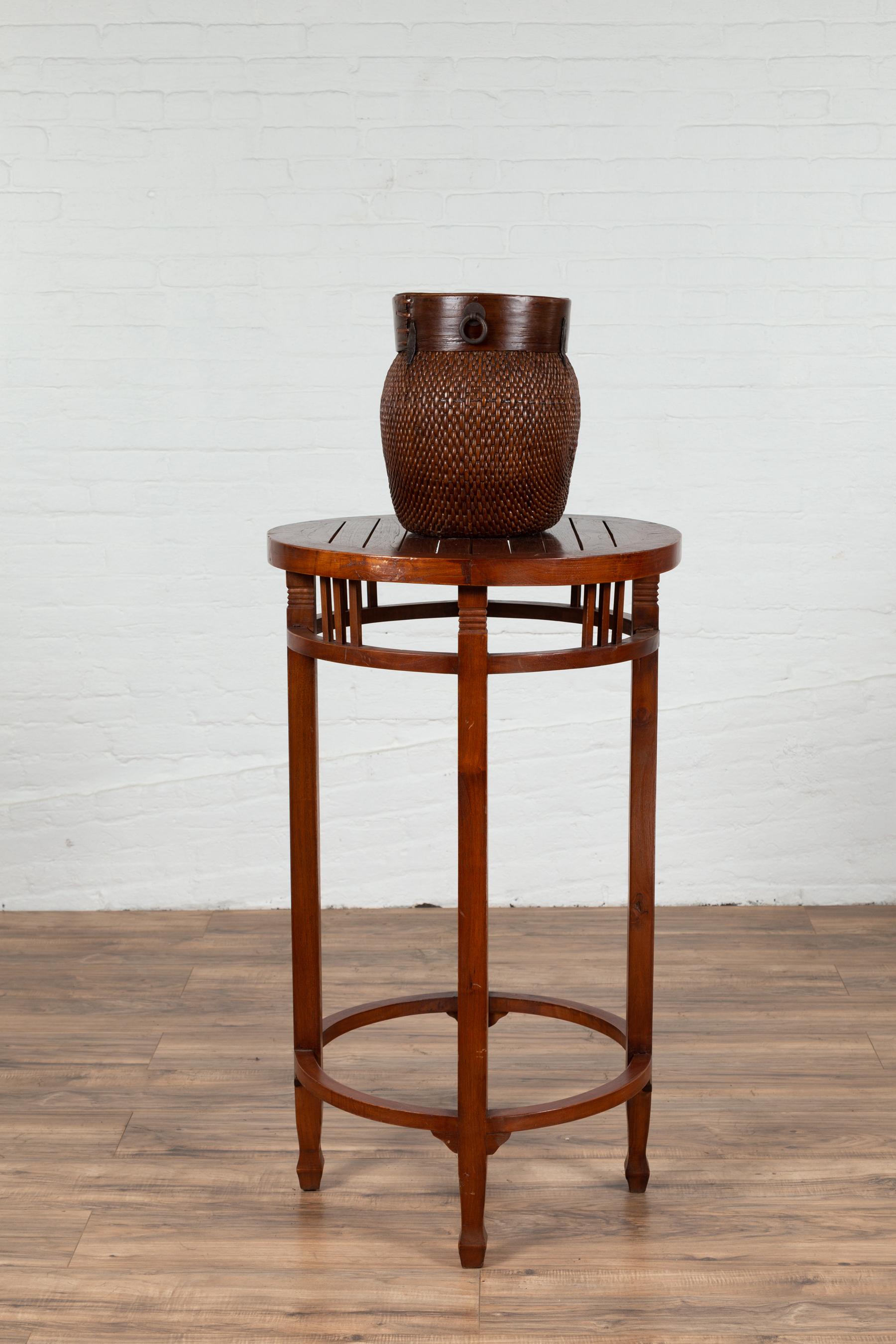 A 19th century Indonesian tall round pedestal table with pierced apron and side stretchers. Found in Java, this elegant pedestal features a circular slatted top sitting above a pierced apron adorned with pillar strut motifs. Four legs, connected to
