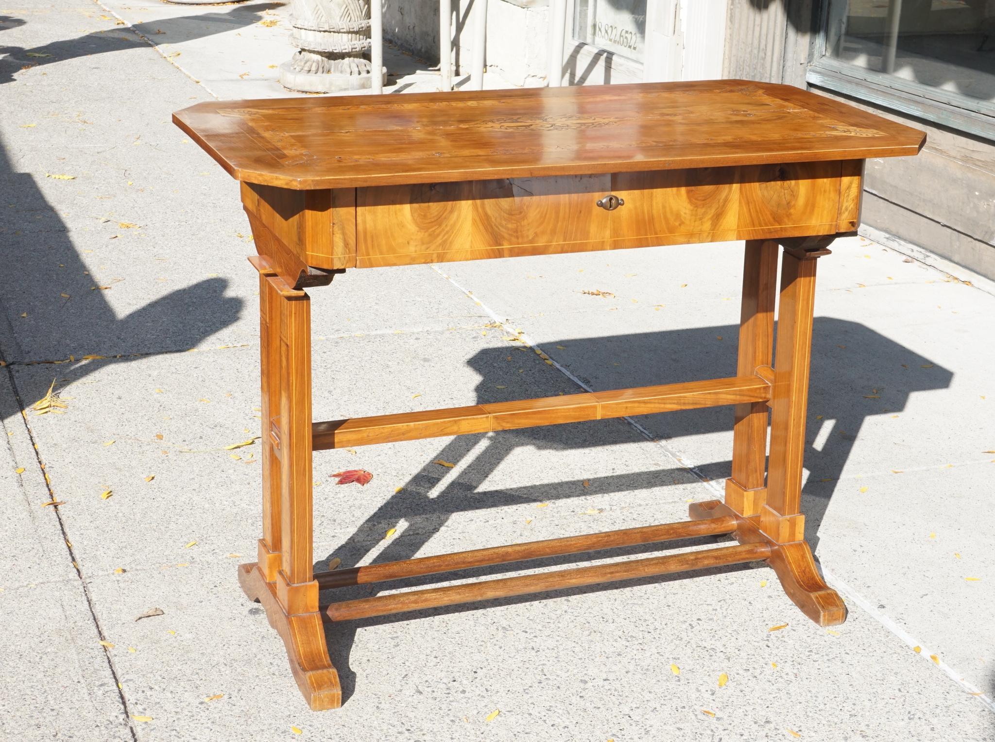 Made circa 1830 this fine table is crafted of walnut, fruitwood and birds eye maple veneers that have been decorated with satinwood inlays. The writing surface is accompanied by one long drawer in the apron. The decorative pattern of the inlay